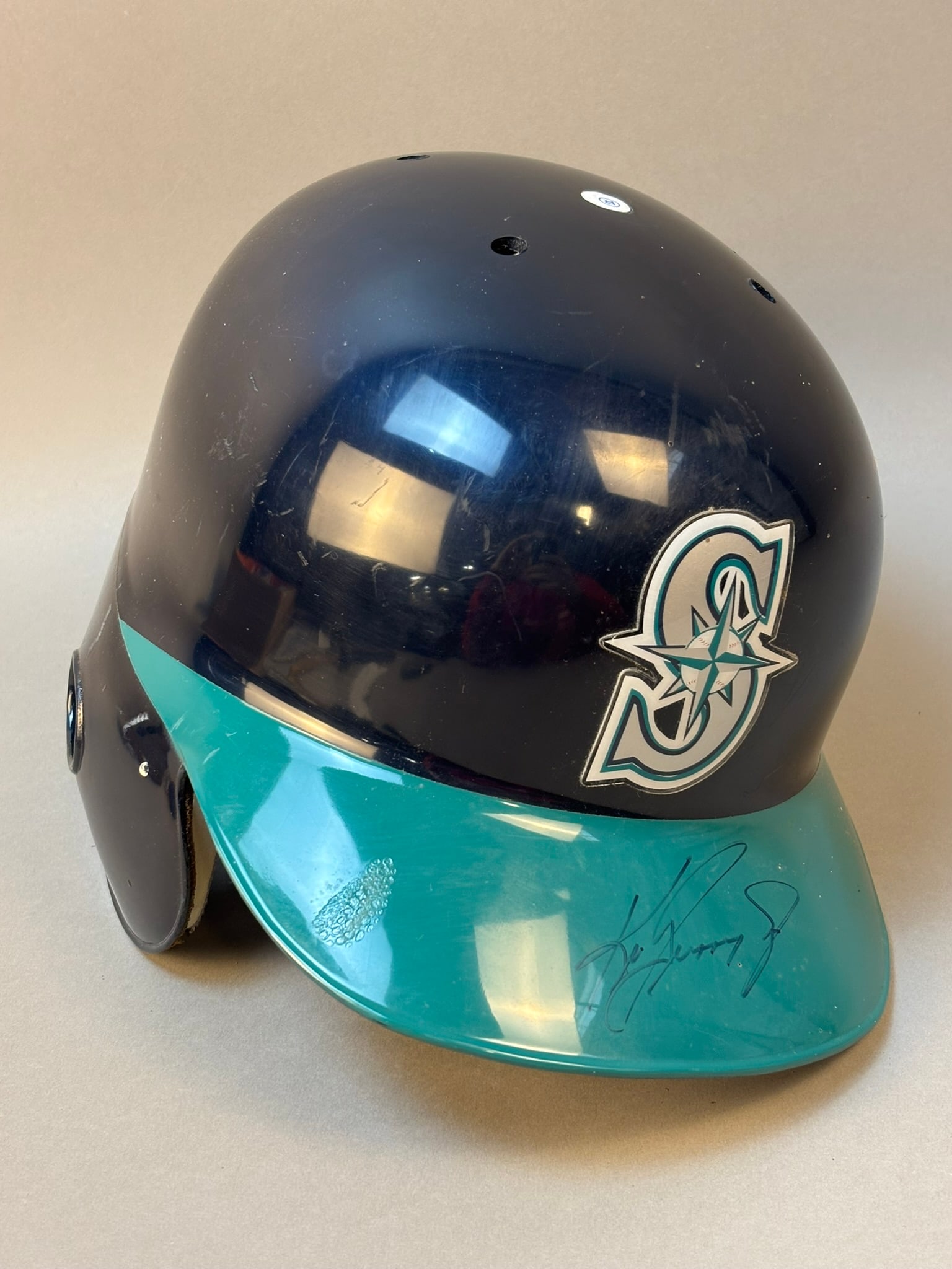 Ken Griffey Jr Signed Team Issued Seattle Mariners Batting Helmet: Official Seattle Mariners navy and teal batting helmet signed boldly on the brim in black marker by Hall of Famer Ken Griffey Jr. Signature presents prominently against the teal visor and displays