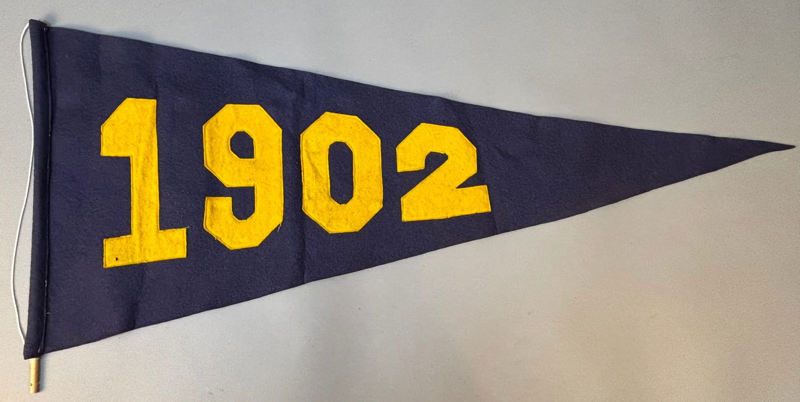 1902 University of Michigan Wolverines Original 33" Football Pennant: Outstanding early 20th century University of Michigan wool felt pennant, dated 1902, measuring approximately 33 inches in length. Constructed in deep navy wool with large applied maize felt numerals,