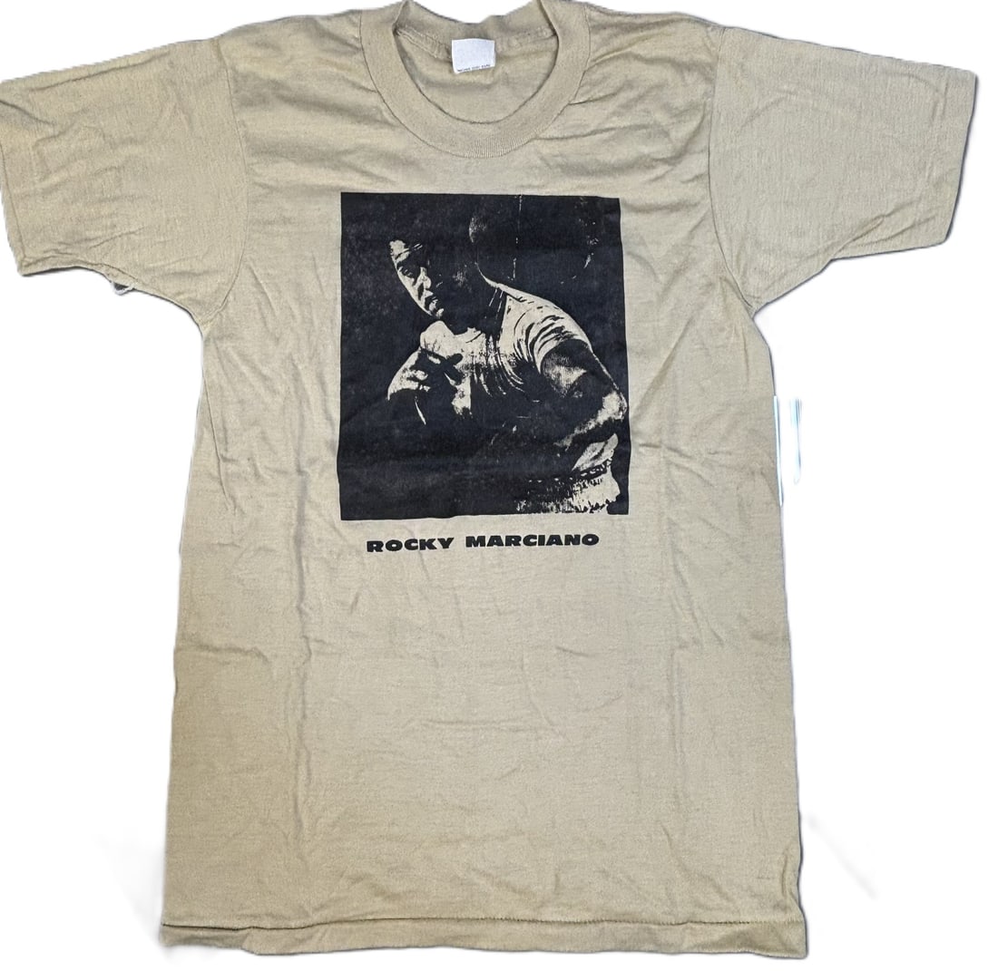 Rocky Marciano Original 1970s Screen Stars Boxing T-Shirt Size Small: Incredible original Rocky Marciano t-shirt by Screen Stars. Size small. PLEASE NOTE WE OFFER IN HOUSE SHIPPING & HAVE BIDDING AVAILABLE ON OUR OWN WEBSITE! If you win on LIVE AUCTIONEERS, please click