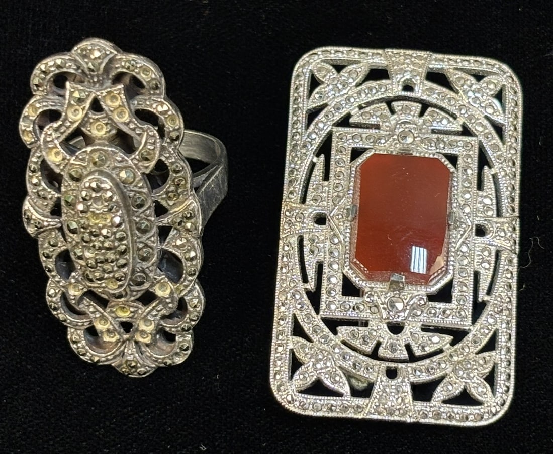 Art Deco Sterling Marcasite Coral Brooch & Marcasite Ring Size 8: Two piece sterling silver jewelry lot including an Art Deco style rectangular brooch set with marcasite stones surrounding an octagonal red cabochon stone consistent with coral, together with a marcas
