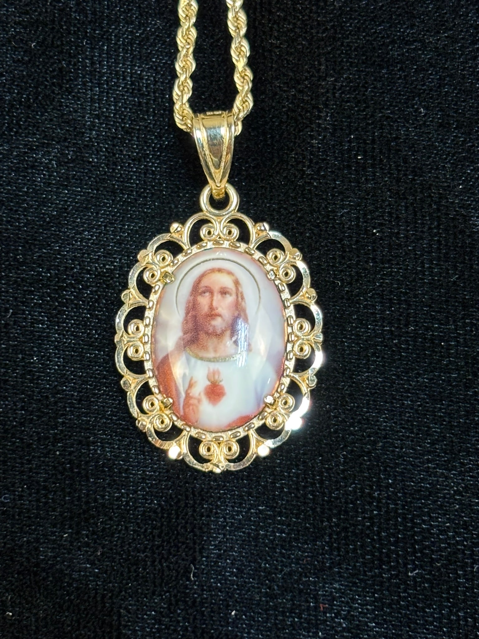 14K Gold Sacred Heart Jesus Pendant Necklace Religious Medal 8.96 Grams: 14K yellow gold necklace featuring an oval Sacred Heart of Jesus devotional medal pendant. The pendant displays a color portrait of Christ with Sacred Heart motif framed by an ornate openwork gold bor