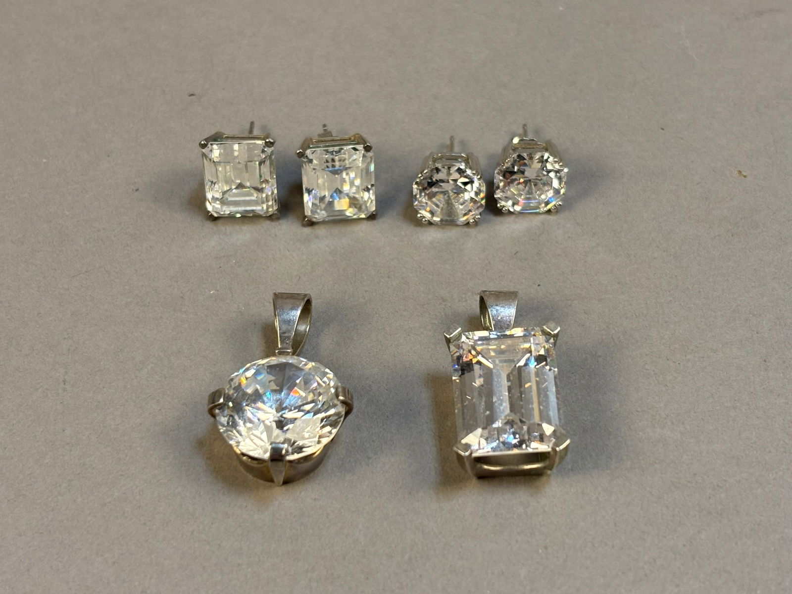 Sterling Silver CZ Jewelry Lot Stud Earrings & Large CZ Pendants 12.45g: Group of sterling silver jewelry set with large faceted clear cubic zirconia stones including two pairs of stud earrings and two pendant necklaces. The earrings feature square and round brilliant styl