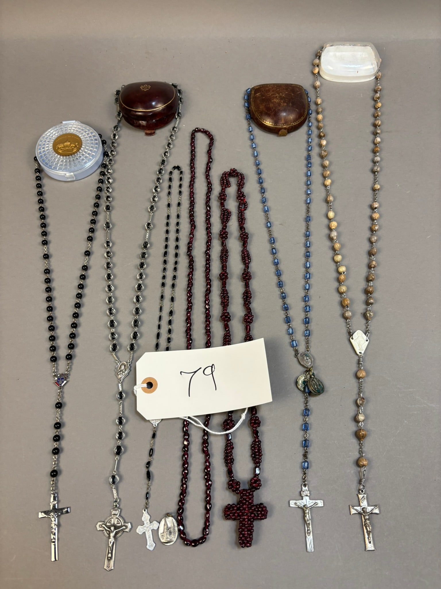 Lot 7 Sterling Silver Catholic Rosaries Crucifixes Medals Prayer Beads Cases: Collection of seven Catholic rosaries featuring sterling silver crucifixes and devotional medals, paired with a variety of bead types including black glass, clear faceted beads, deep red glass beads,