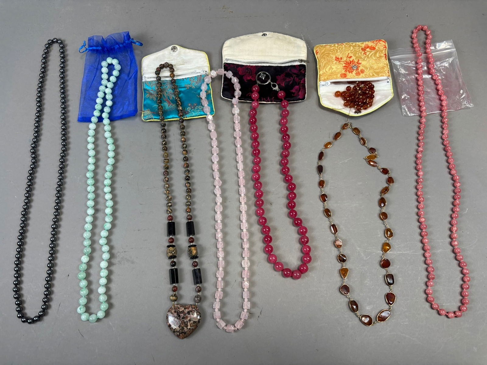 Lot 8 Vintage Stone Bead Necklaces Rose Quartz Amber Jade Hematite Pendant: Group lot of eight assorted vintage bead necklaces featuring a variety of semi-precious and decorative stone materials. Included are strands composed of polished hematite beads, green marbled