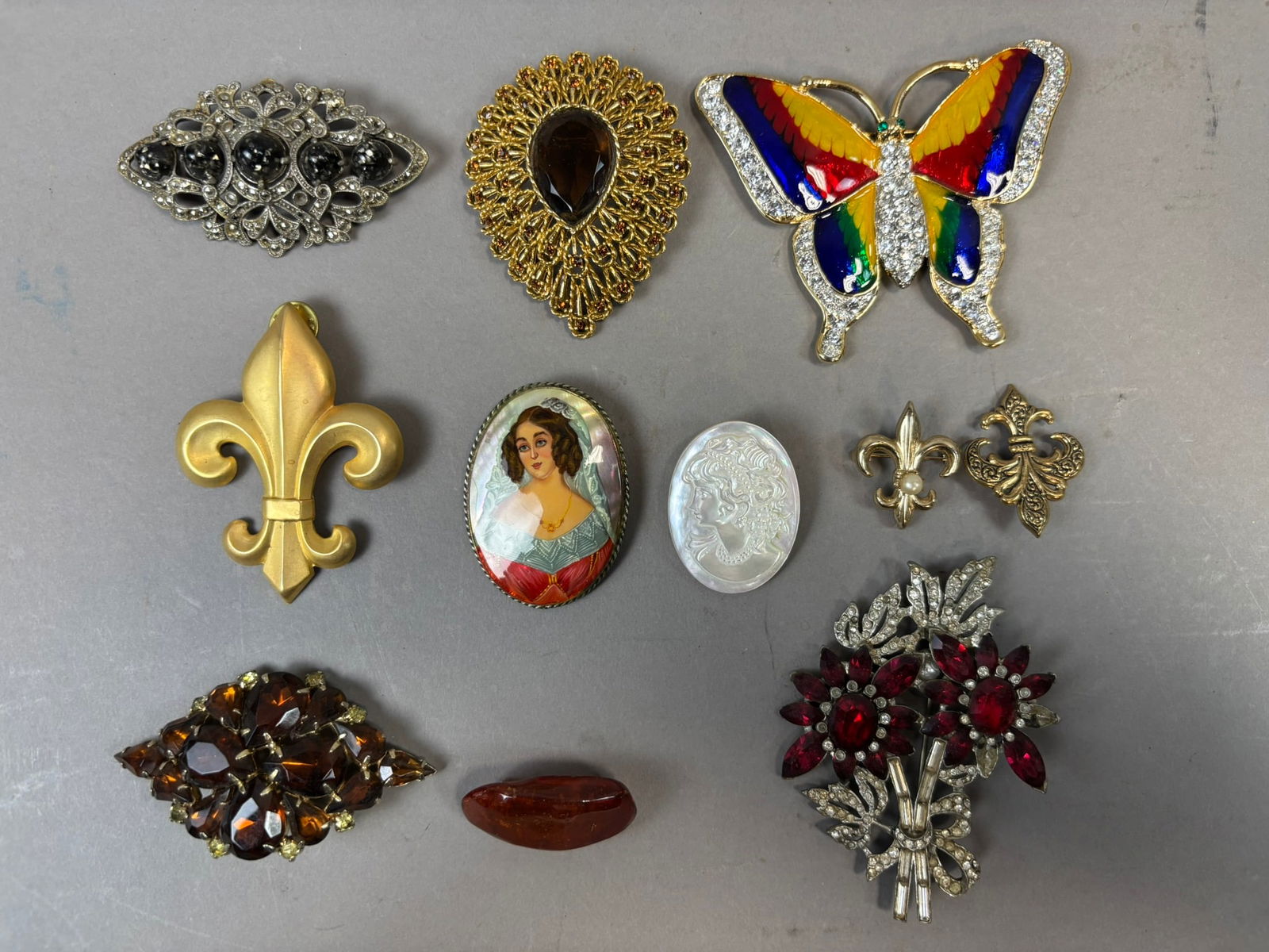 Vintage Brooch Lot Rhinestone Butterfly Portrait Cameo Fleur De Lis Pins: Group of eleven vintage brooches and pins featuring a variety of decorative styles and materials including a large multicolor enamel rhinestone butterfly brooch, gold tone fleur de lis pin, amber tone