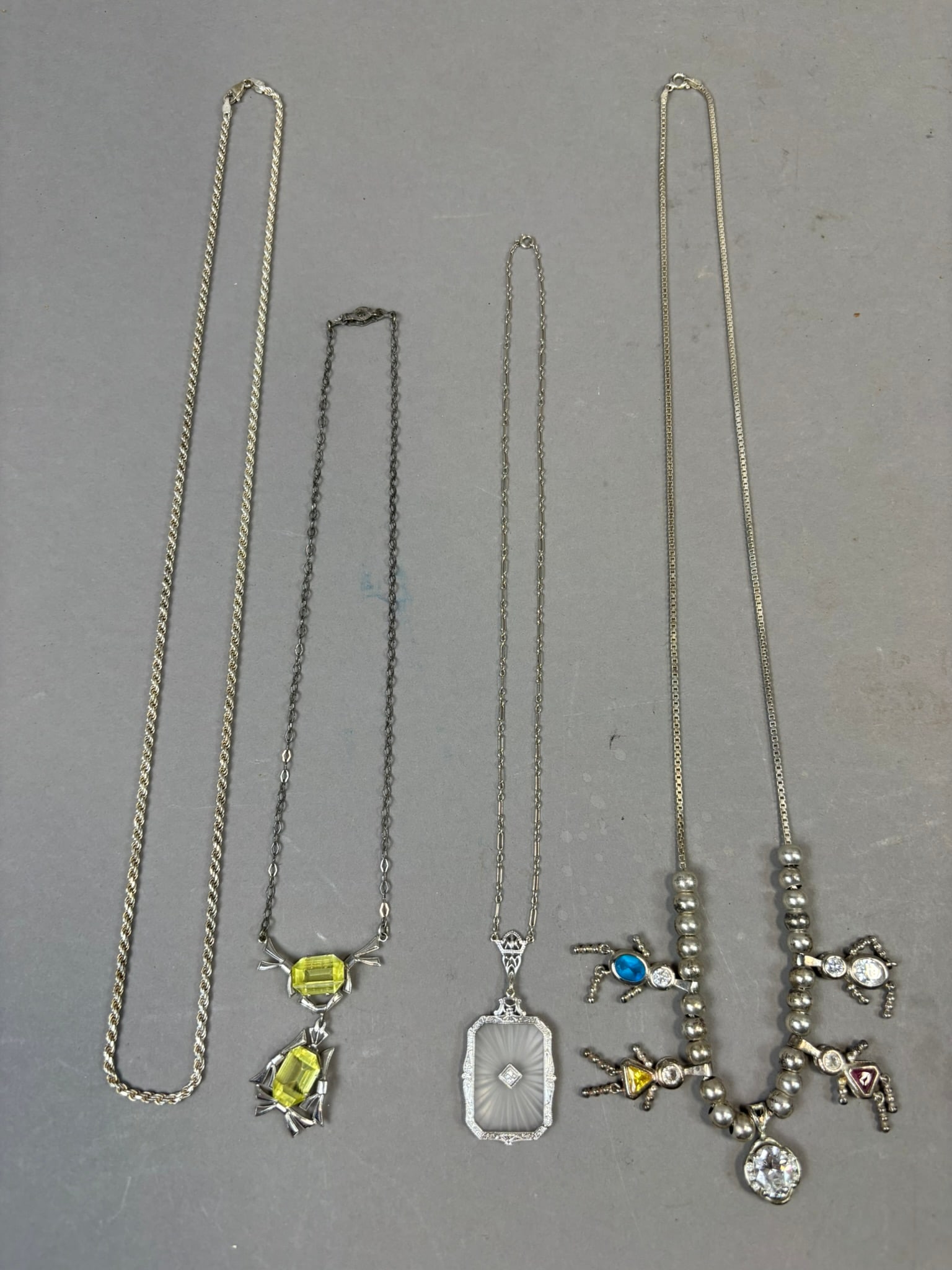 Four Sterling Silver Necklaces Art Deco Filigree Spider Charm Bead Pendant 48.7 Grams: Group of four sterling silver necklaces including a two-tone rope chain marked Italy 925, an Art Deco style necklace set with bright yellow faceted stones in an ornate geometric mount, a rectangular