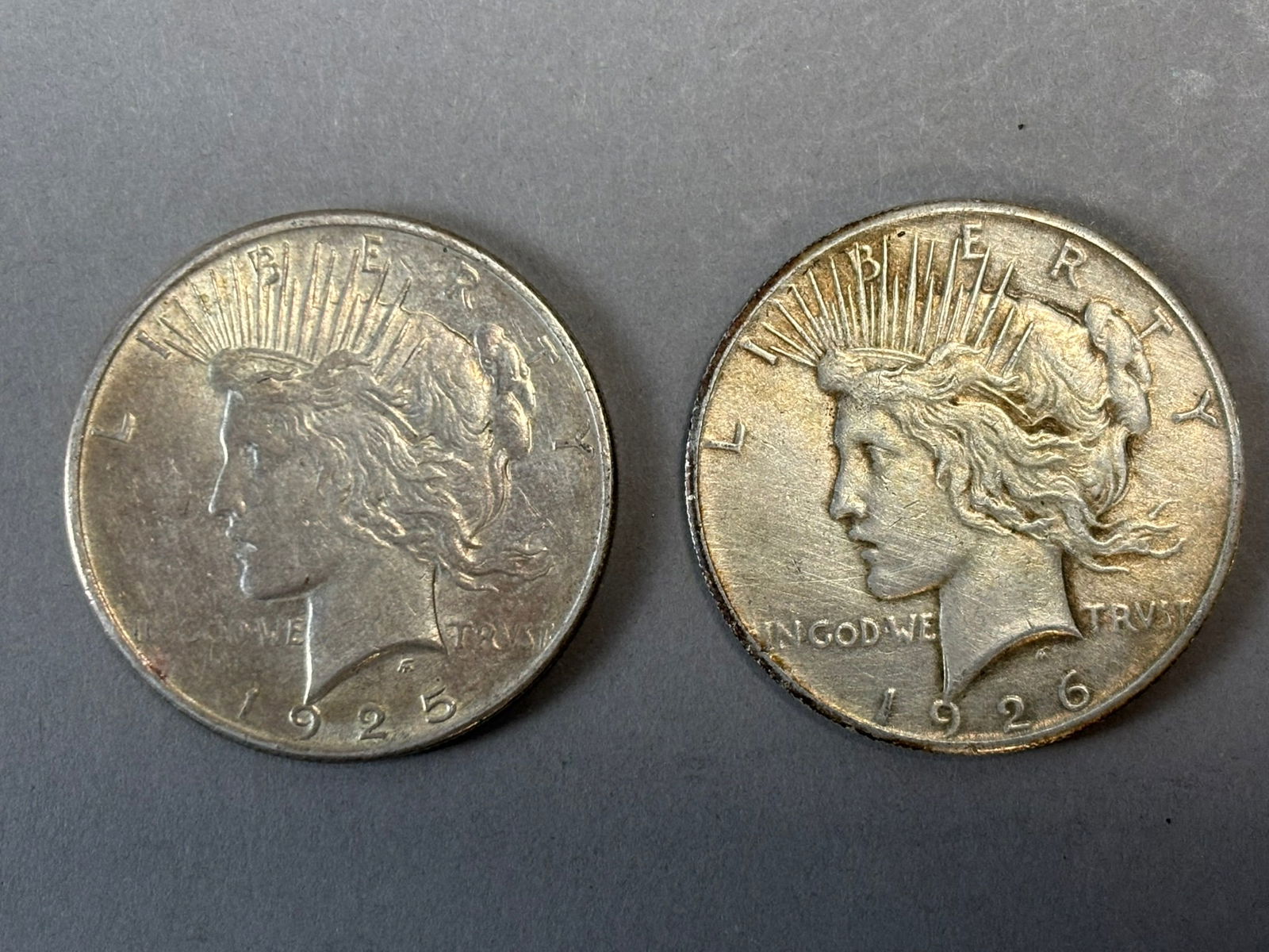 1925 & 1926 Peace Silver Dollars Pair 53.4g Combined US $1 Coins: Pair of United States Peace silver dollars dated 1925 and 1926, struck in 90% silver and designed by Anthony de Francisci, featuring the iconic Liberty portrait with radiant crown on the obverse and
