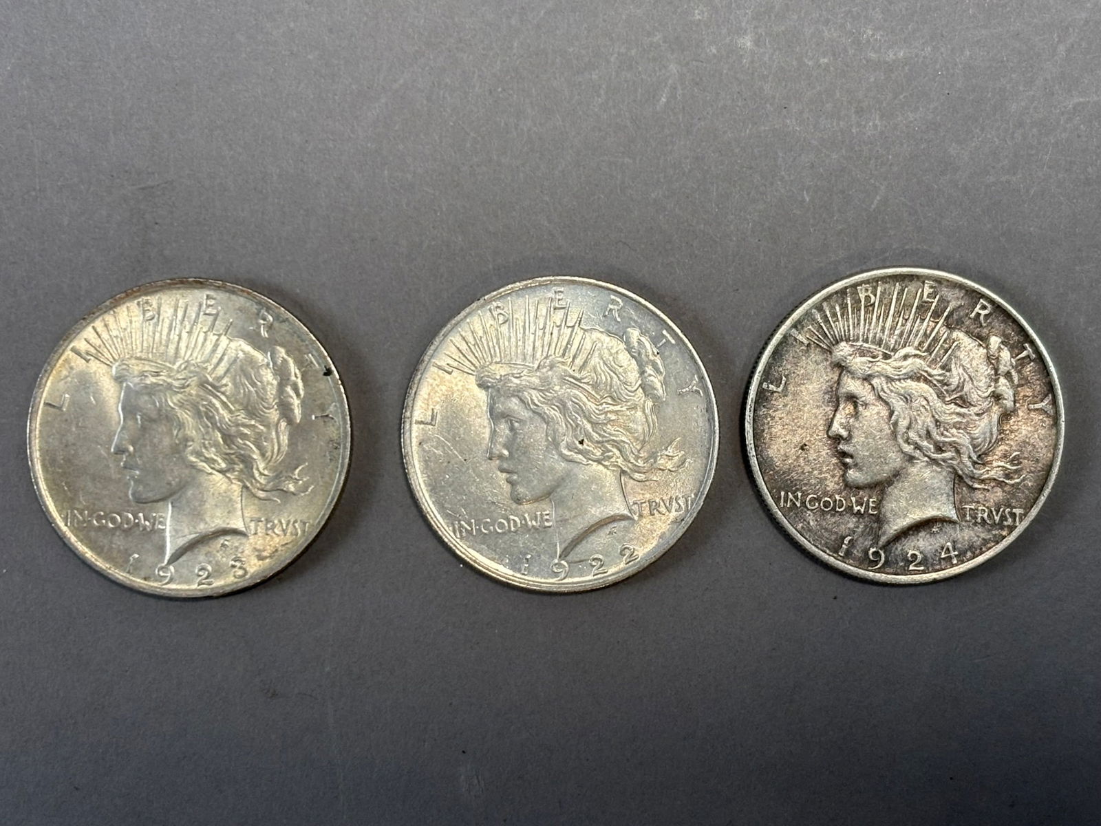 1922 1923 1924 Peace Silver Dollars Trio 80.3g Combined US $1 Coins: Group of three United States Peace silver dollars dated 1922, 1923, and 1924, struck in 90% silver and designed by Anthony de Francisci to commemorate peace following World War I. The obverse