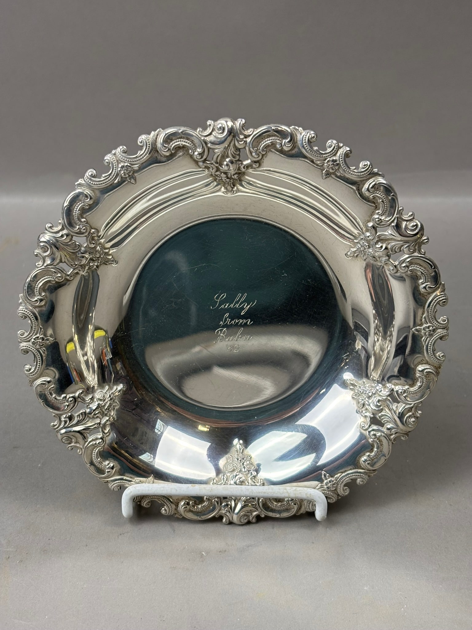 Wallace Sterling Repousse Rim Small Plate Engraved Bowl 80 Grams: Sterling silver decorative bowl by Wallace, marked “Wallace Sterling 5523” on the underside and featuring an ornate repousse rim with elaborate rococo-style scrolling and floral ornament s