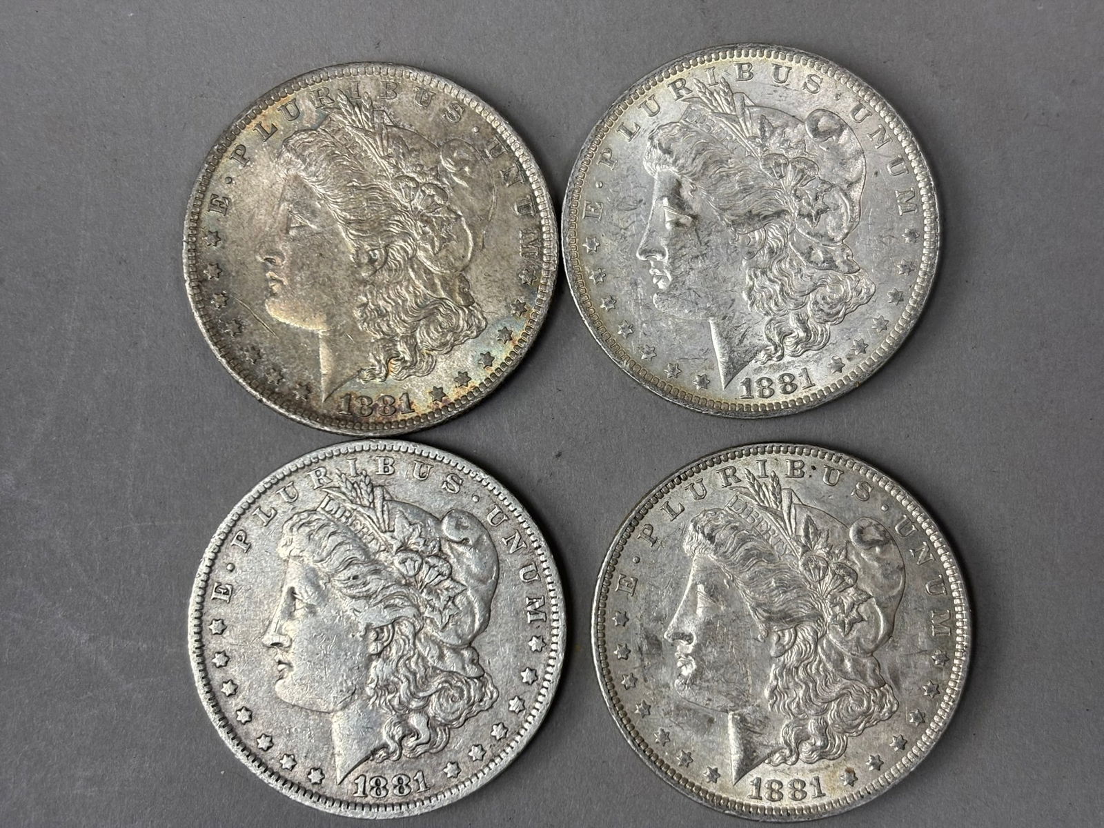 Antique Lot 4 1881 Morgan Silver Dollars Mixed Circulated Condition: Group of four United States Morgan silver dollars dated 1881, each featuring the Liberty head obverse and eagle reverse designed by George T. Morgan. The coins show circulated condition with visible w