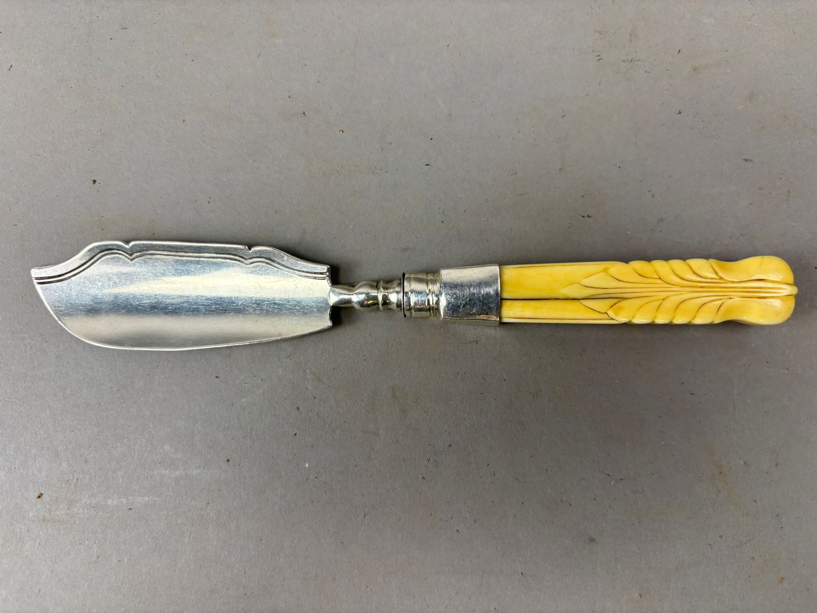 Antique English Silver Fish Server w Carved Bone Handle 44g: Antique English silver fish server featuring a finely shaped and engraved blade with decorative stepped cresting along the spine and a carved handle resembling ivory or bone with a feathered foliate