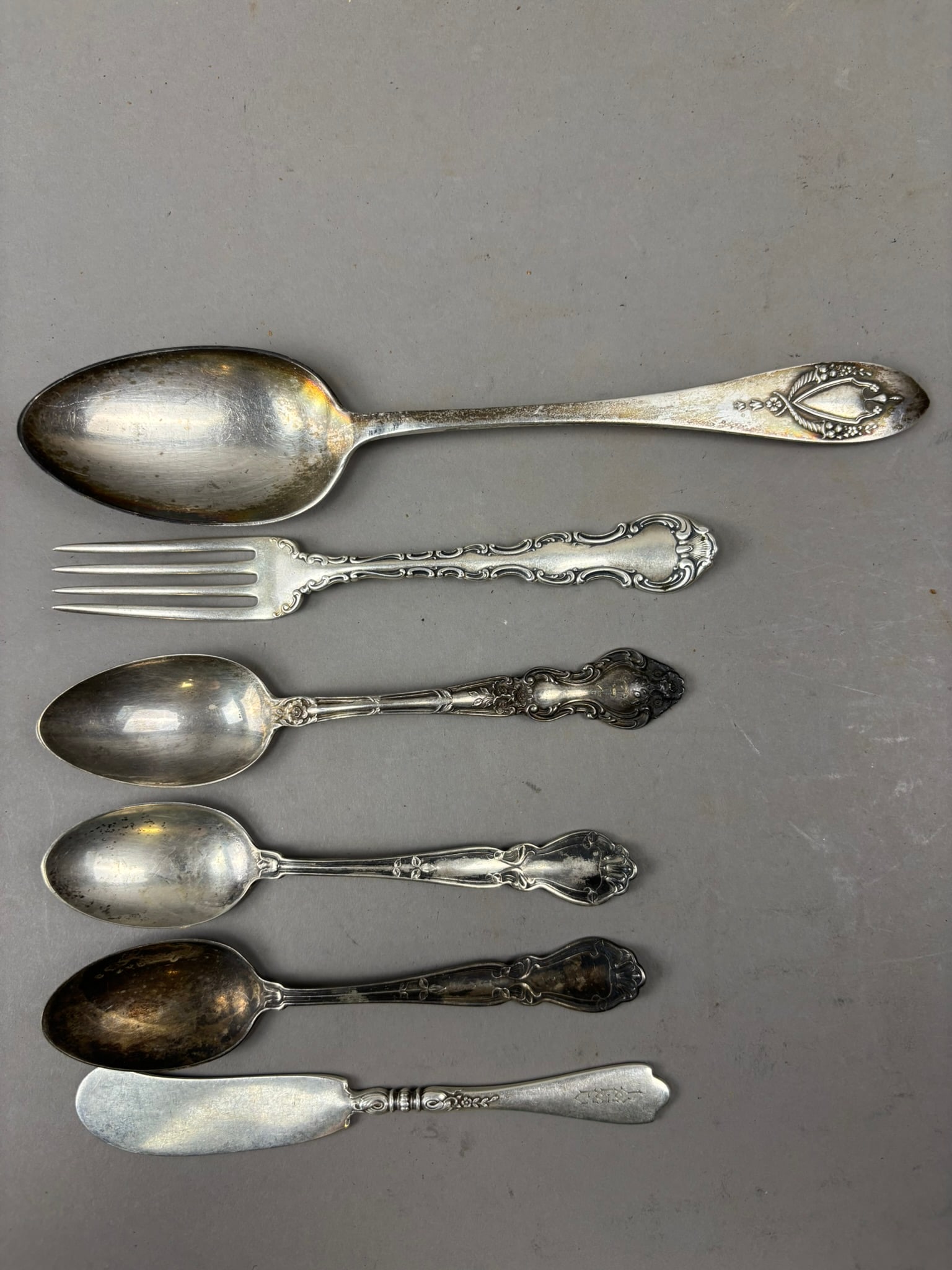 Group of 6 Sterling Silver Flatware Pieces 170g Mixed Patterns: Group lot of six assorted sterling silver flatware pieces including spoons, a fork, and a butter knife featuring a variety of decorative patterns and makers, several clearly marked “SterlingR