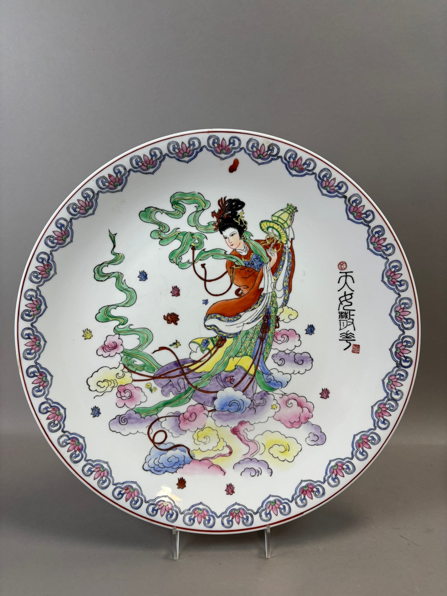 Chinese Famille Rose Celestial Maiden Plate Qianlong Mark 20th C 16": Large Chinese porcelain charger decorated in famille rose enamels depicting a celestial maiden floating among stylized clouds while holding a lantern, surrounded by a decorative floral and scroll bord