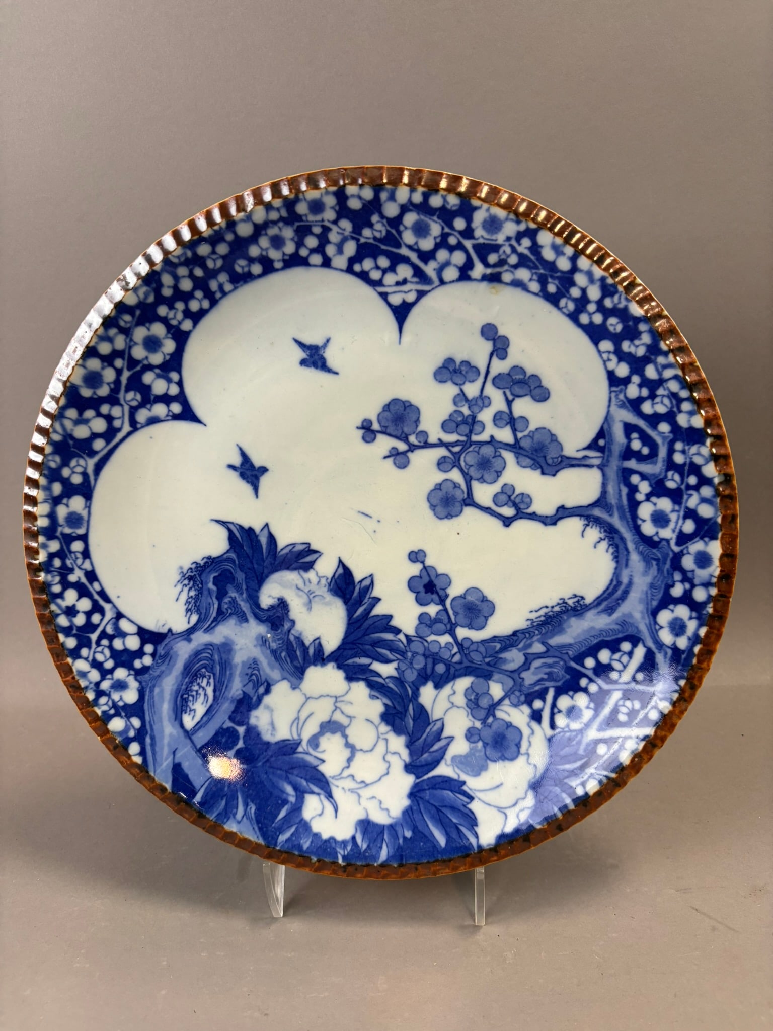 Chinese Export Blue & White Porcelain Plate Floral Prunus Motif Brown Rim: Chinese export porcelain plate decorated in underglaze cobalt blue with a stylized prunus blossom and flowering tree scene set within a quatrefoil reserve, surrounded by a dense floral and blossom gro
