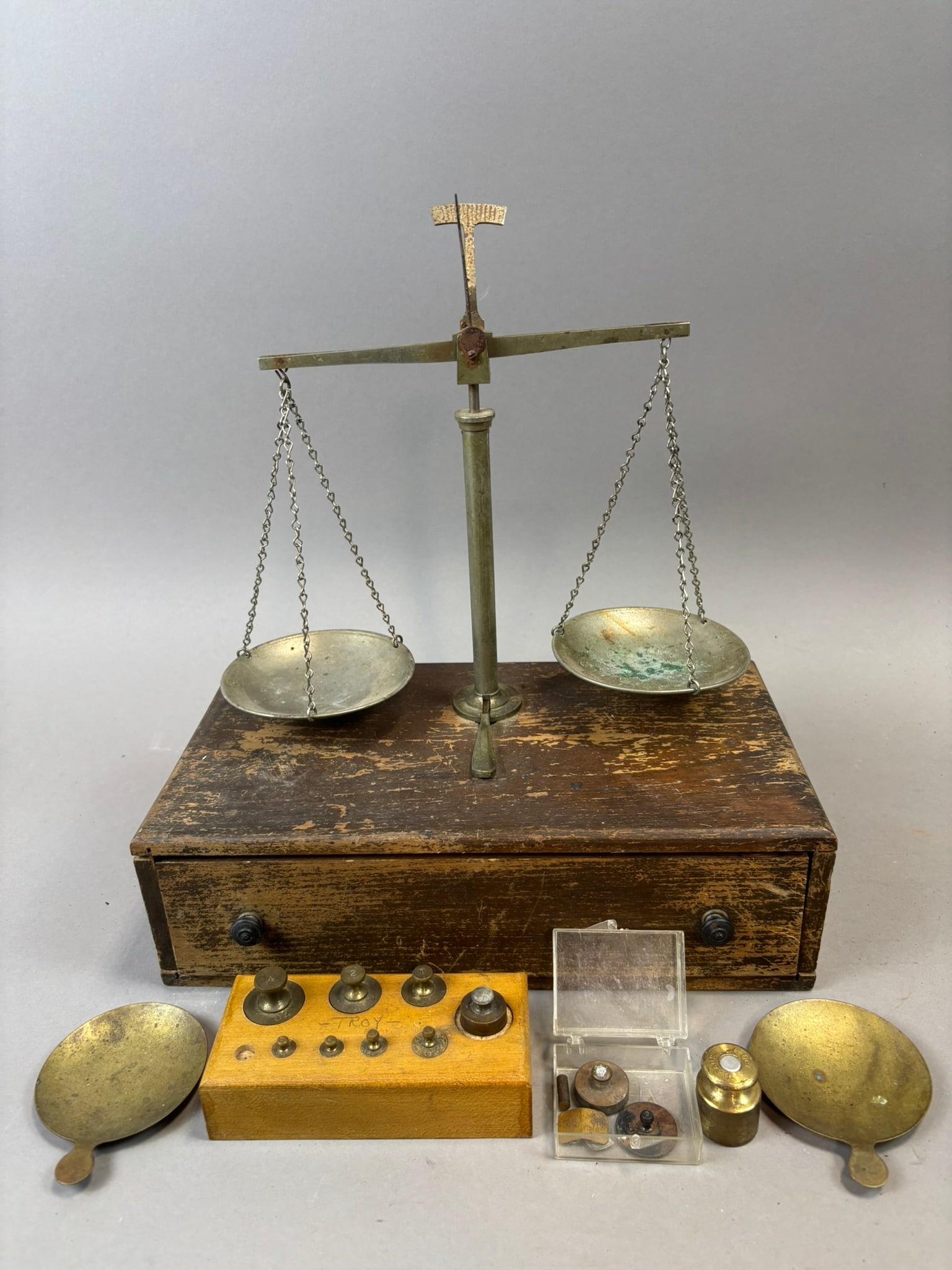 Antique Brass Apothecary Balance Scale Wood Base Weights Scientific Set: Antique brass apothecary or laboratory balance scale mounted on a rectangular wooden base with integrated storage drawer containing assorted brass calibration weights and accessories. The scale featur