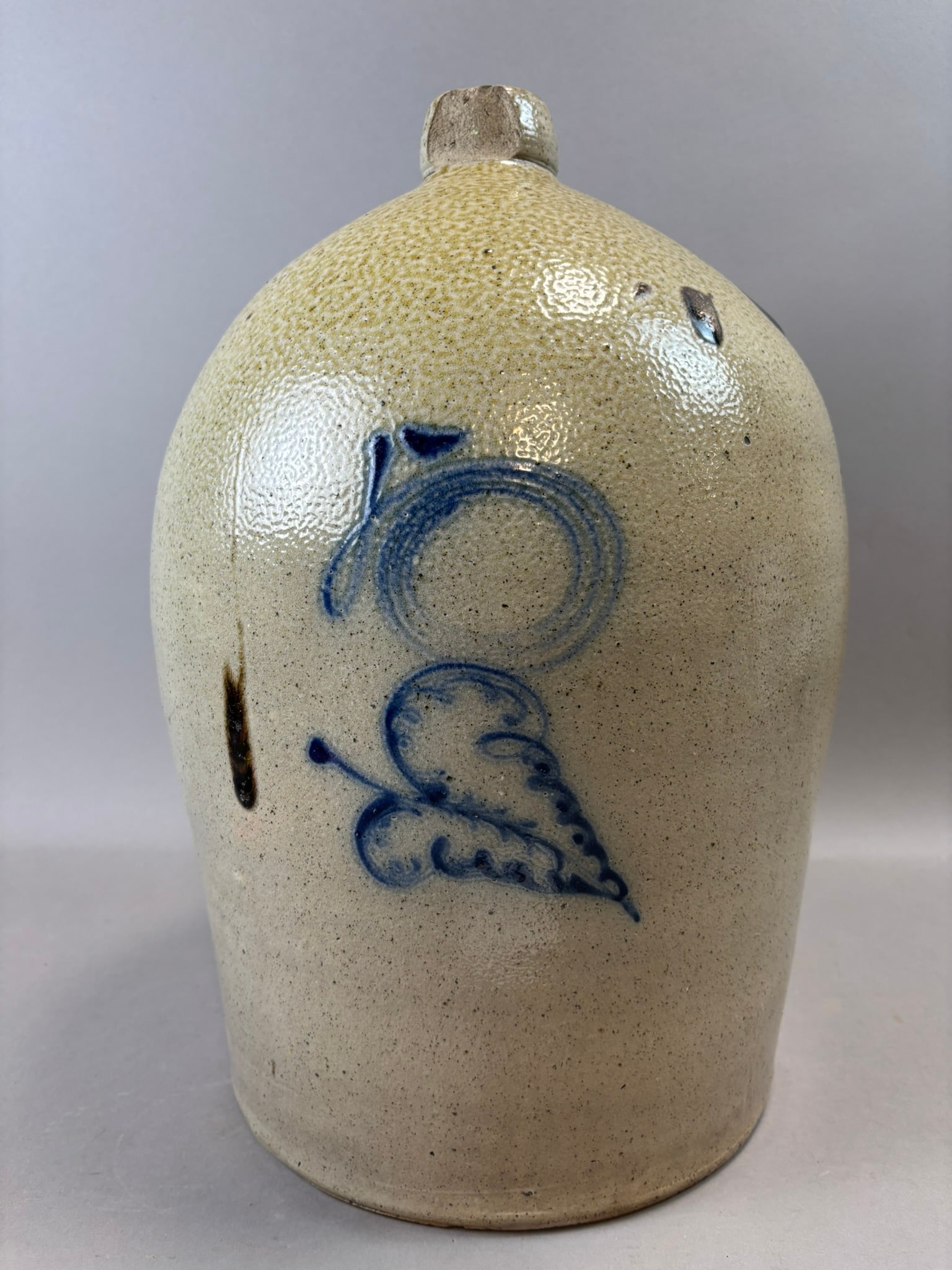Antique Cobalt Decorated Stoneware Jug 18” Salt Glaze 5 Gallon Jug: Attractive 19th century cobalt decorated American stoneware jug featuring bold brushed blue slip decoration in a classic circular and foliate motif. The form is tall and ovoid with squared spout lip a