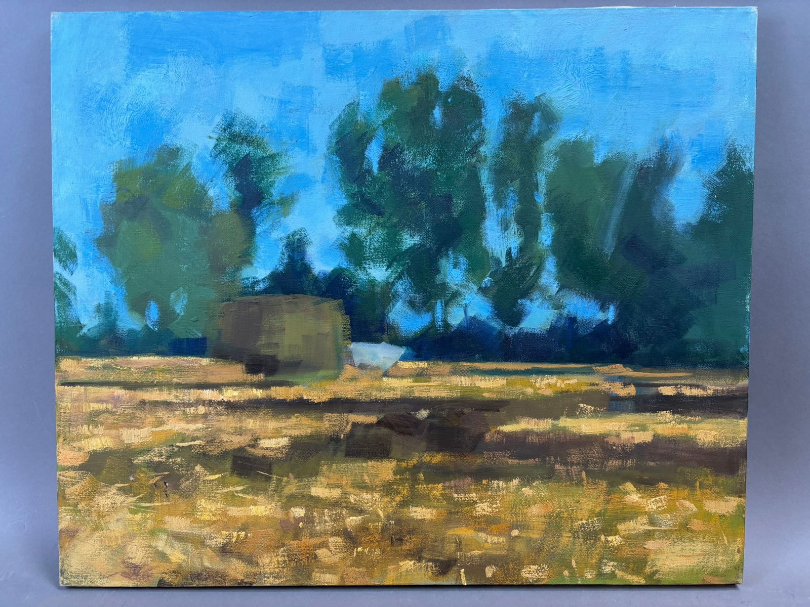 Henry Schafer Landscape Oil Painting Farm Field & Trees 24 x 20: Oil on canvas landscape painting by Jackson, Michigan artist Henry Schafer depicting a rural field with a low farm structure set against a distant tree line beneath a bright blue sky. Executed with ex