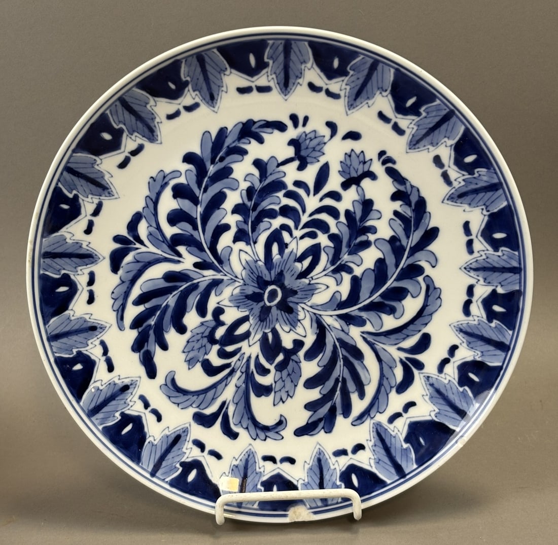 Delft Blue Hand Painted Charger Floral Scroll Decoration 10.25 Inch Plate: Decorative Delft style blue and white ceramic charger or plate featuring a finely hand painted floral scroll and foliate design radiating from the center with a stylized leaf border. The piece measure