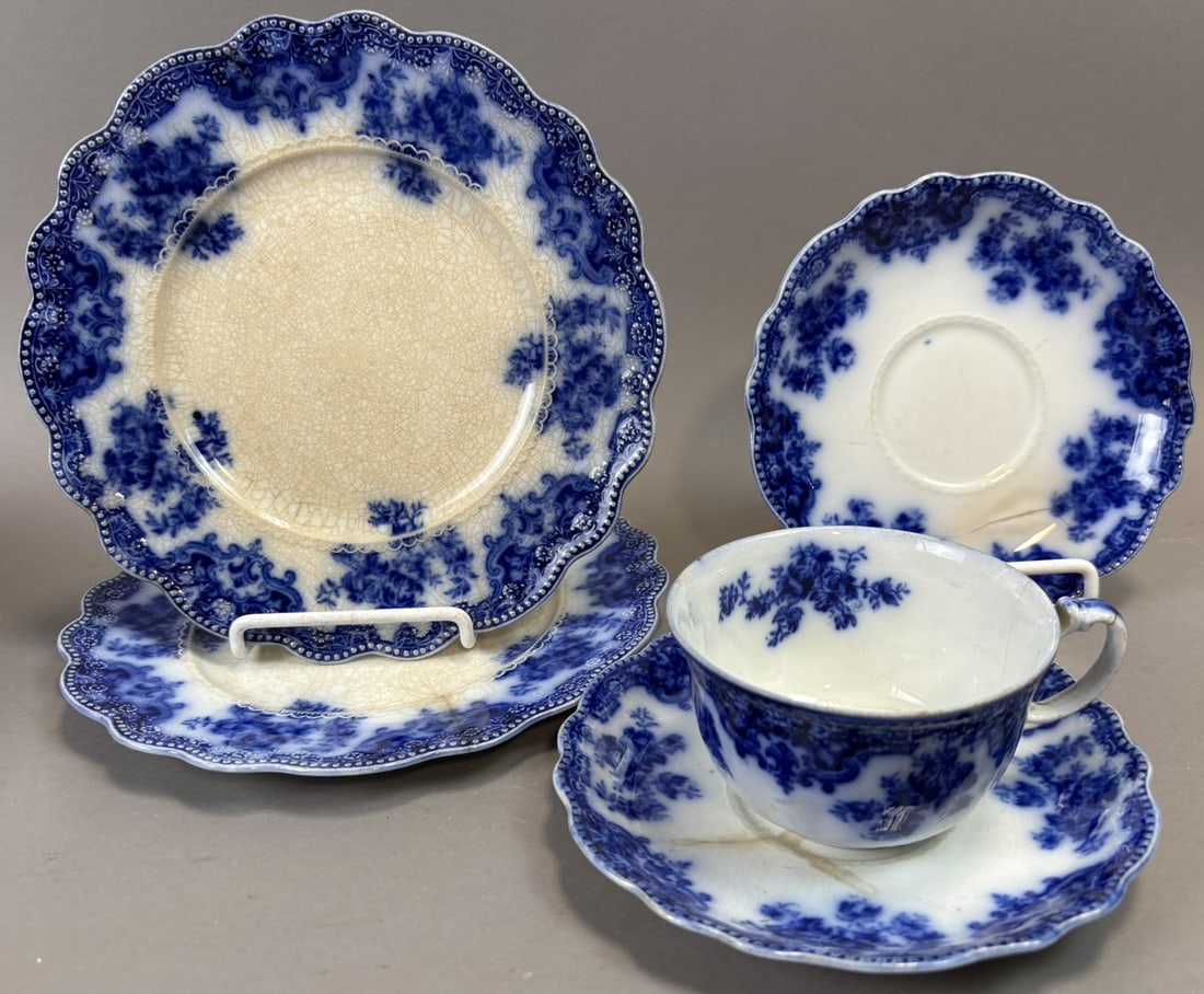 Five Pieces Flow Blue Porcelain Tea Cup Saucer Plate Set C.S. Osborne: Five pieces of antique English flow blue porcelain including a teacup with matching saucer and three additional plates in a richly decorated floral and scrollwork border pattern. The set displays the