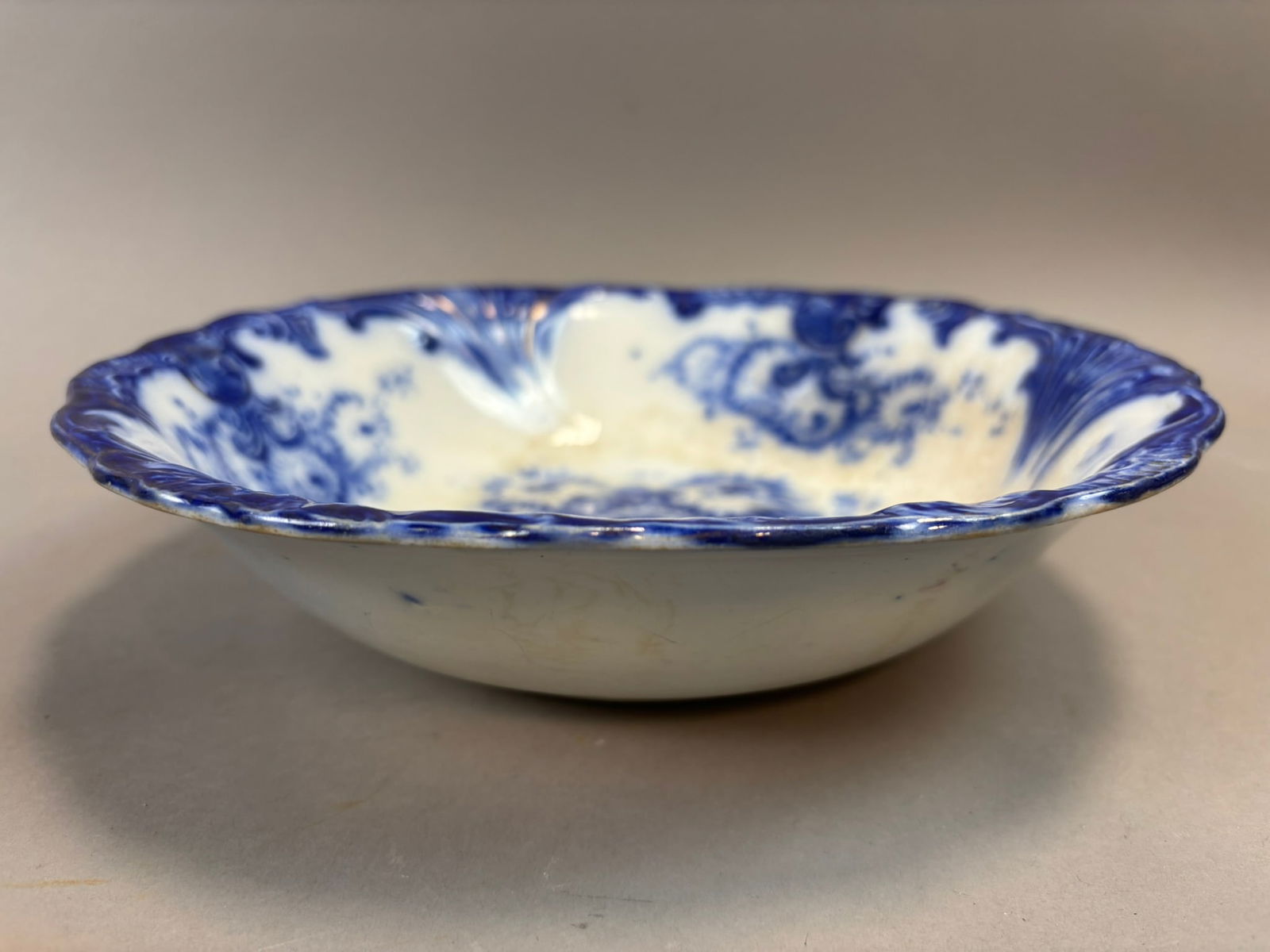 Antique Flow Blue Porcelain Serving Bowl John Mier & Son Scalloped Rim 10in: Antique flow blue porcelain serving bowl featuring a molded scalloped rim with raised Rococo style scrollwork and a central chrysanthemum floral bouquet decoration. The bowl measures approximately 10