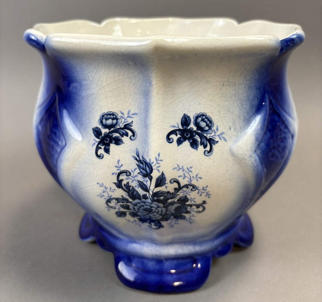 Flow Blue Floral Jardiniere Cache Pot Planter Blue Footed 7in x 6.5in: Decorative flow blue porcelain jardiniere or cache pot featuring a floral transfer decoration with cobalt shaded panels and raised molded body. The planter has a scalloped rim and stands on an integra