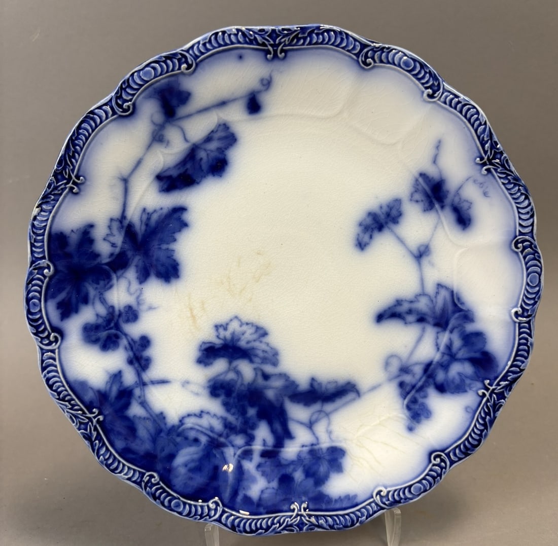 Lonsdale England Flow Blue Semi Porcelain Plate Grape Vine Pattern 10": Flow blue semi-porcelain plate produced by Lonsdale, England, featuring a grape vine motif with flowing foliage and fruit encircling the rim. The plate displays a molded decorative border with repeati