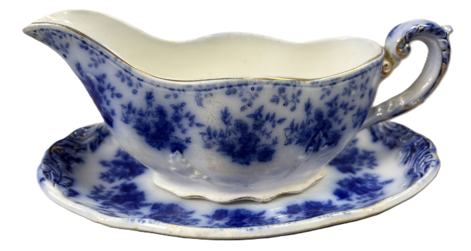 Flow Blue Gravy Boat & Underplate Set Staffordshire Semi Porcelain: Two piece flow blue gravy boat and matching underplate in a delicate floral transfer pattern with molded scroll rim decoration. The gravy boat features an elegant curved handle with gilt highlights an