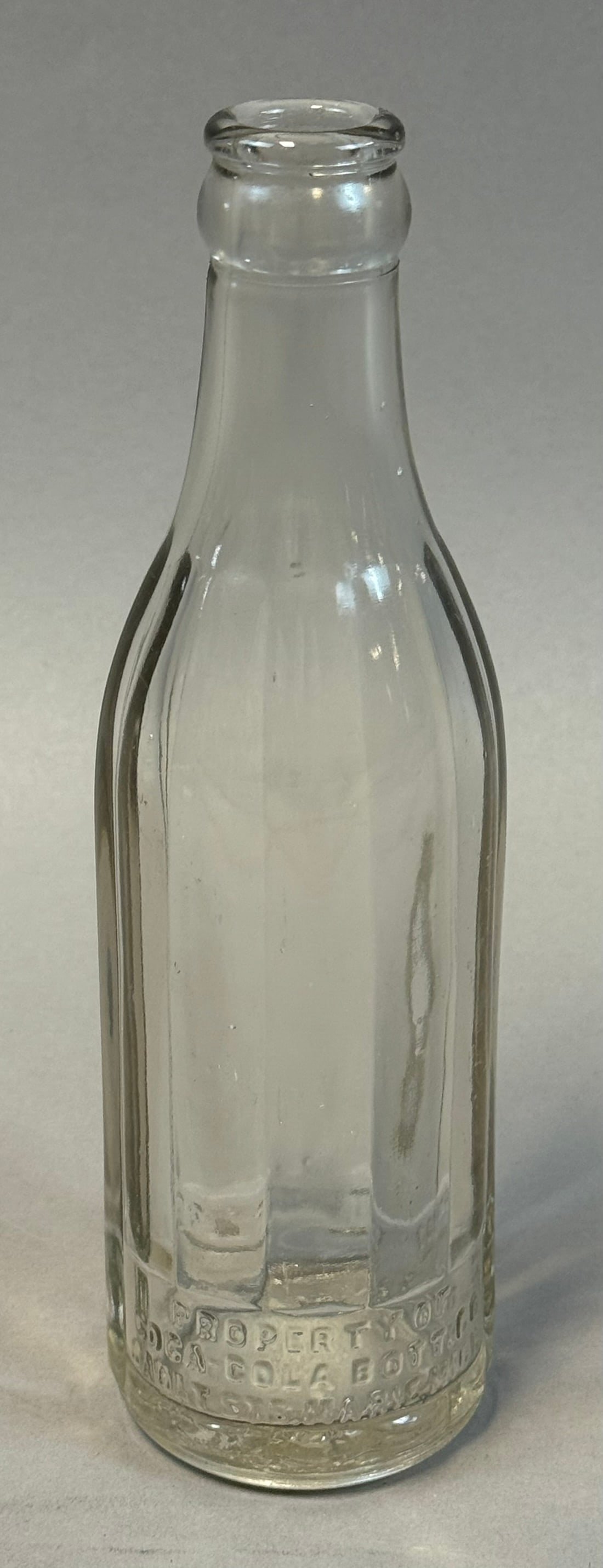 Early Coca Cola Hobble Skirt Panel Bottle Clear Glass 6.5oz: Early 20th century Coca-Cola hobble skirt panel bottle in clear glass featuring vertical ribbed design transitional between straight-sided and fully contoured forms; embossed PROPERTY OF COCA-COLA BOT