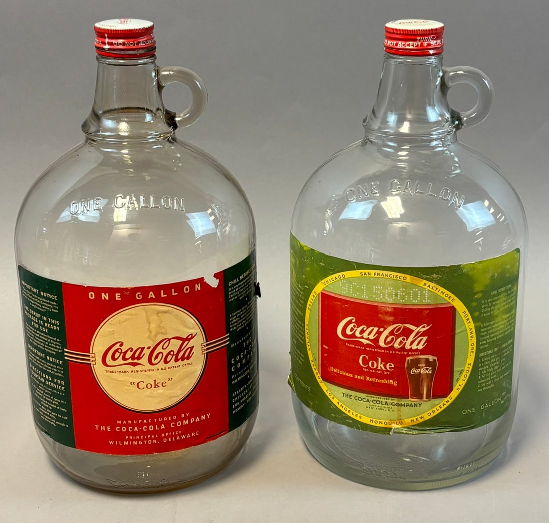 Pair Vintage 40s 50s Coca Cola 1 Gallon Syrup Bottles w/ Paper Label: Pair of vintage Coca-Cola one gallon clear glass syrup jugs, each with applied loop handle at neck and original red metal screw caps, featuring embossed ?One Gallon? at shoulder and original paper lab