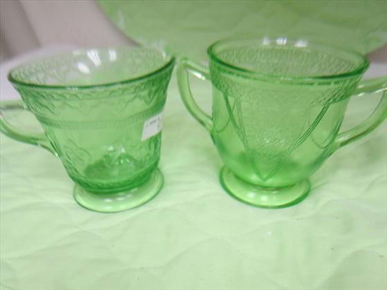 Green depression glass creamer and sugar: Green depression glass creamer and sugar - flower basket design on sugar geometric on creamer - 3" footed