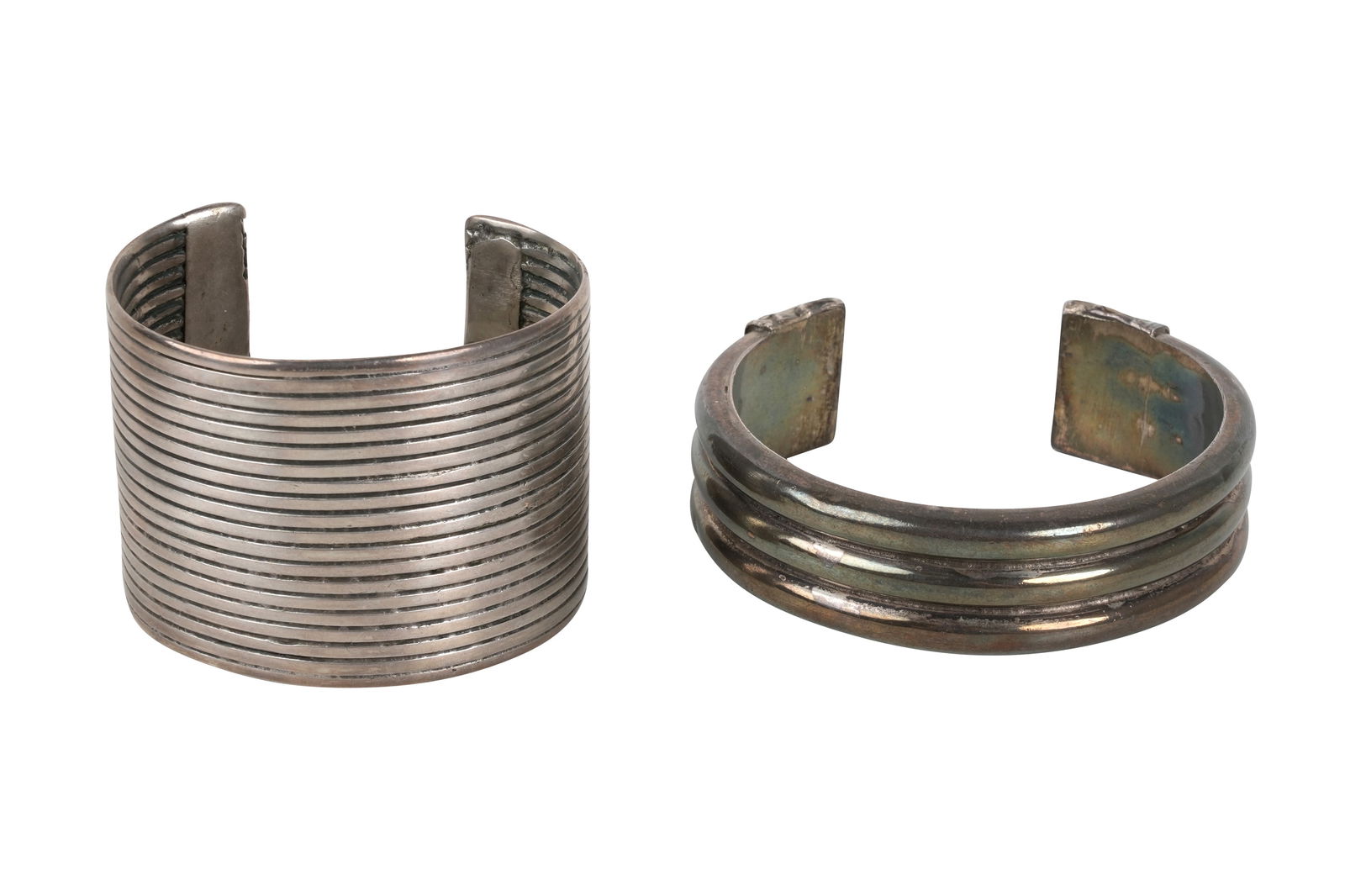 TWO INDIAN SILVER CUFF BRACELETS India, second half 20th century: TWO INDIAN SILVER CUFF BRACELETSIndia, second half 20th century Comprising a bracelet with three overimposed, gadrooned bands, the terminals wrapped with chased silver sheets featuring vegetal motifs,