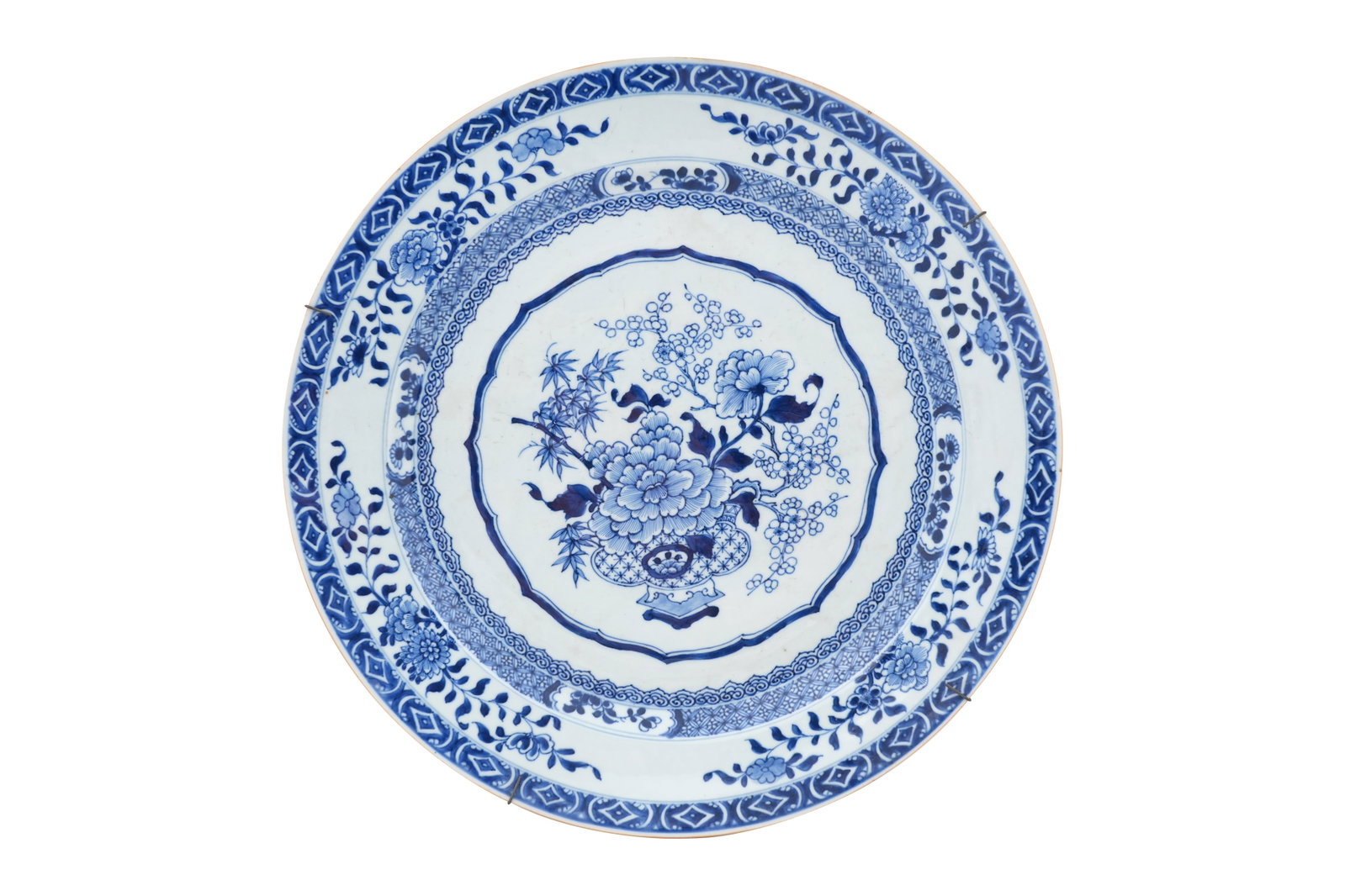 A LARGE CHINESE BLUE AND WHITE CHARGER Qianlong period, 18th century: A LARGE CHINESE BLUE AND WHITE CHARGER Qianlong period, 18th century With a central scalloped cartouche enclosing a vase filled with prunus and peonies surrounded with bands of ruyi-heads, cash and fl