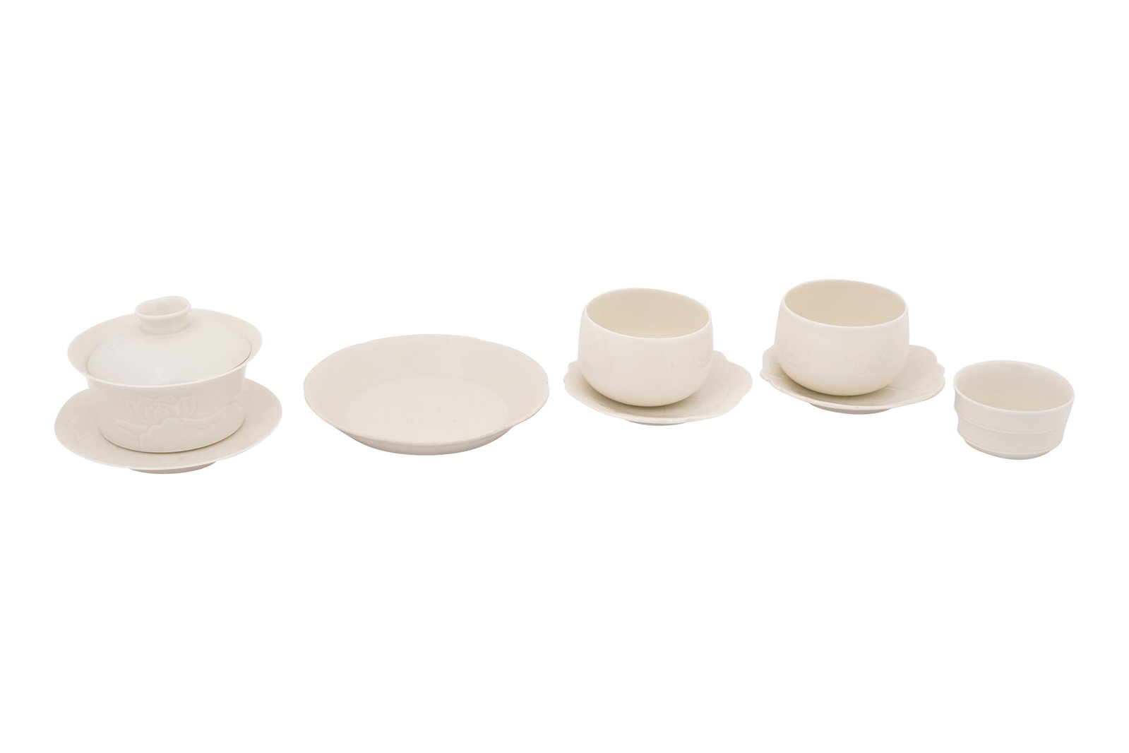 A CHINESE DINGYAO TEA SET Modern: A CHINESE DINGYAO TEA SET Modern Comprising a bowl carved with lotus blossoms and leaves, a stand and a cover, a pair of inscribed cups and saucers formed as lotus leaves, a small bowl and a lobed sau