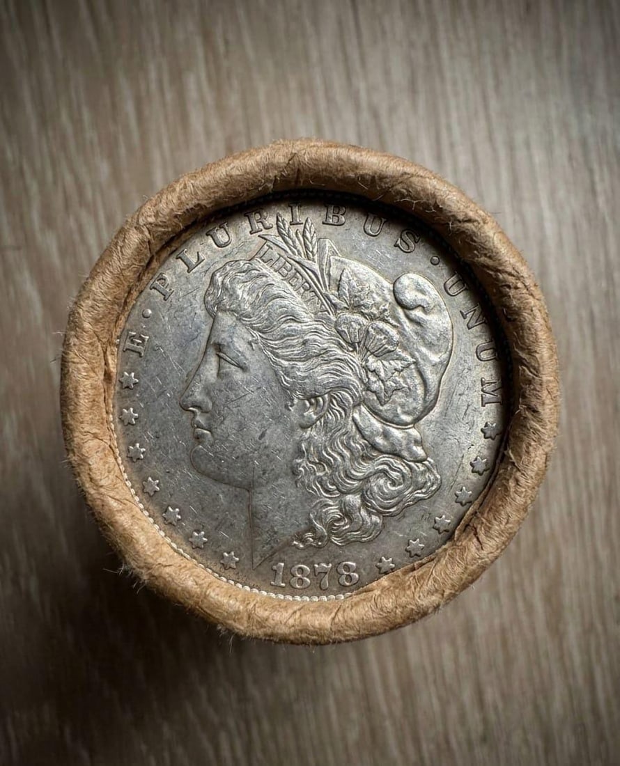 AU $10 Morgan Silver Dollar Roll 1878 & CC Ends: Sealed $10 AU Morgan Dollar roll featuring an 1878 coin on one end and a Carson City (CC) mint example on the other. Interior coins are unexamined due to sealed format. Light wear consistent with AU g