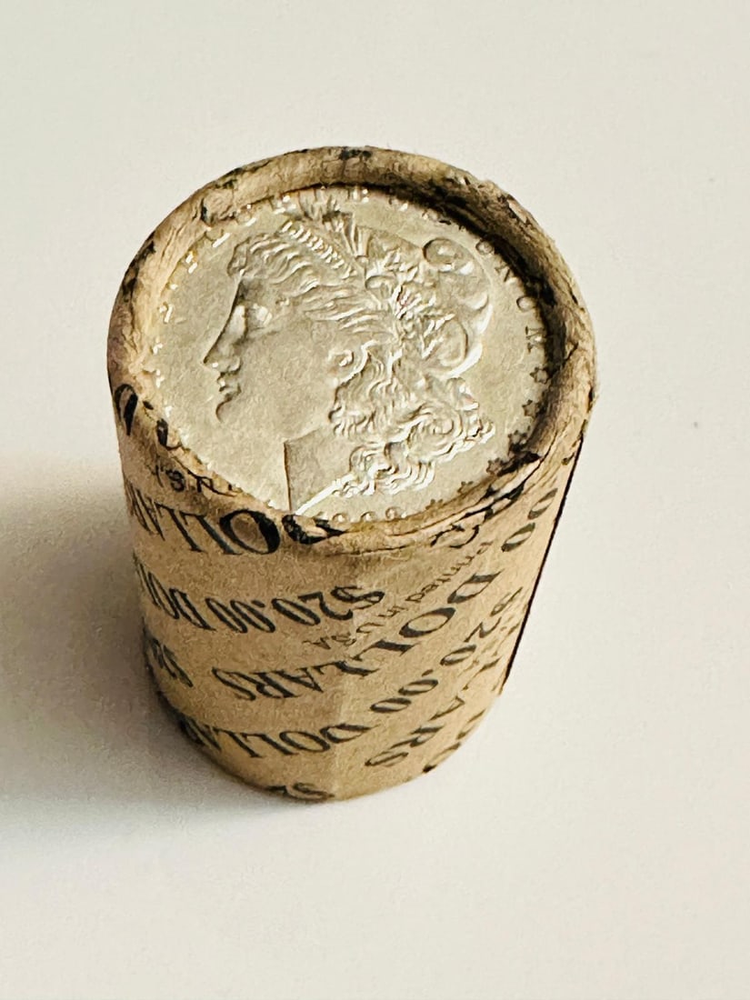 BU $10 Morgan Silver Dollar Roll 1886 & 1897 Ends: An original Brilliant Uncirculated (BU) sealed roll of Morgan Silver Dollars, featuring an 1886 coin on one end and an 1897 coin on the opposite end. The roll remains sealed, with only the front and b
