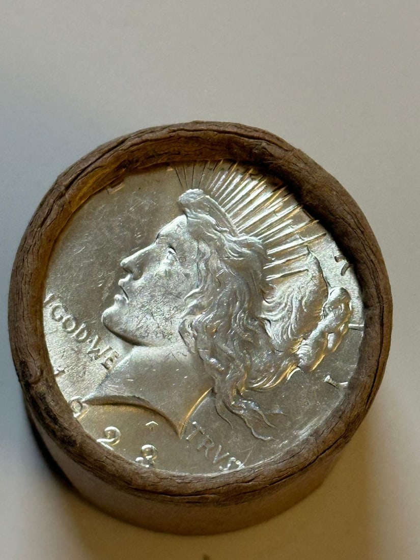 BU $10 Peace Silver Dollar Roll 1925 & 1923 Ends: An original Brilliant Uncirculated (BU) sealed roll containing 10 Peace Silver Dollars, featuring a 1925 coin on one end and a 1923 coin on the other. The roll remains sealed to ensure the interior co