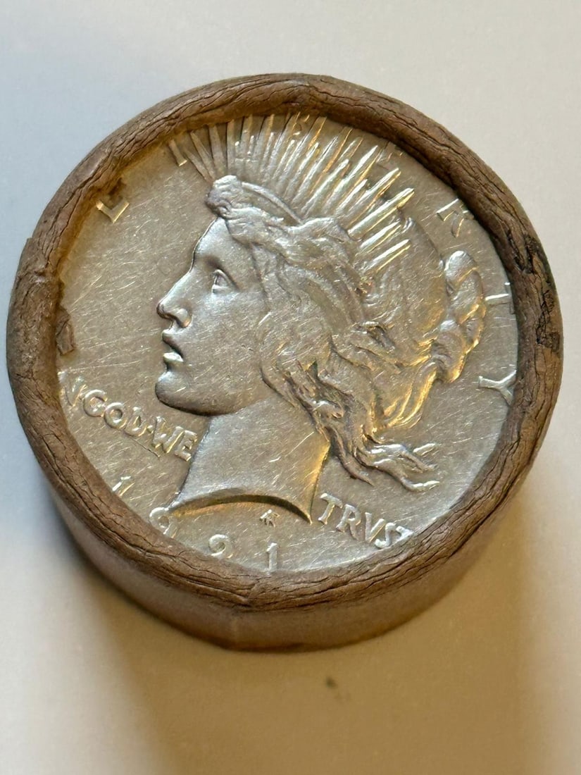 BU $10 Peace Silver Dollar 1921 & 1923 Ends: An original Brilliant Uncirculated (BU) sealed roll containing 10 Peace Silver Dollars, featuring a high-relief 1921 coin on one end and a 1923 coin on the other. The roll remains sealed to ensure the