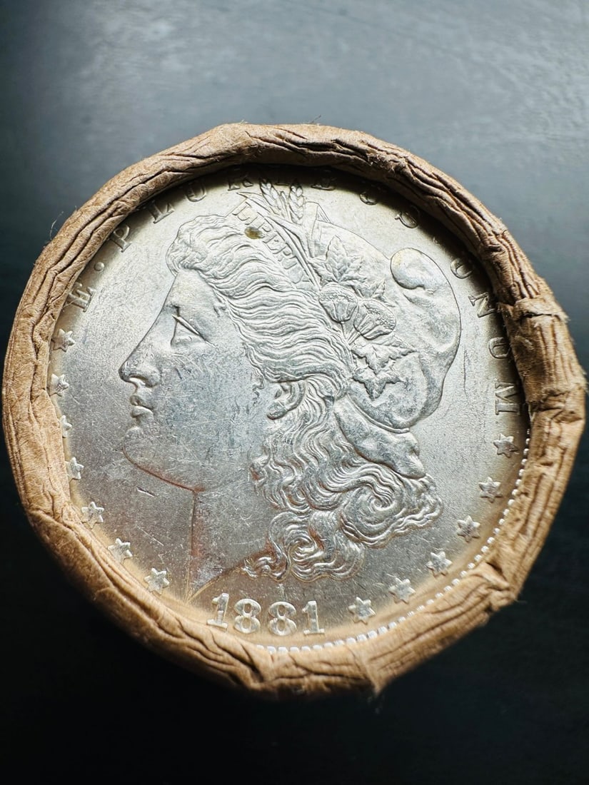 BU $10 Morgan Silver Dollar Roll 1881 & CC Ends: An original Brilliant Uncirculated (BU) sealed roll of Morgan Silver Dollars, featuring an 1881 coin on one end and a Carson City (CC) Mint coin on the opposite end. The roll remains sealed, with only
