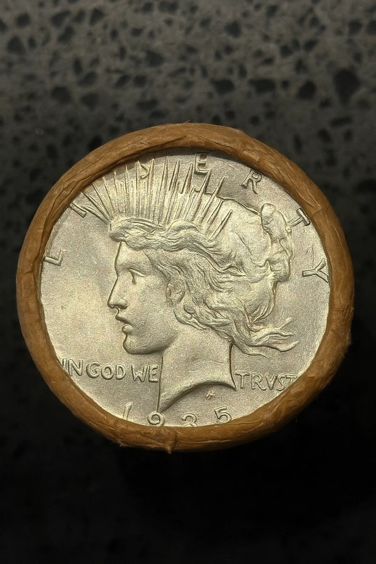 BU$10 Peace Silver Dollar Bank Roll 1935 & 1925 Ends: An original Brilliant Uncirculated (BU) sealed bank roll containing 10 Peace Silver Dollars, featuring a 1935 coin on one end and a 1925 coin on the other. The roll remains sealed to ensure the interi