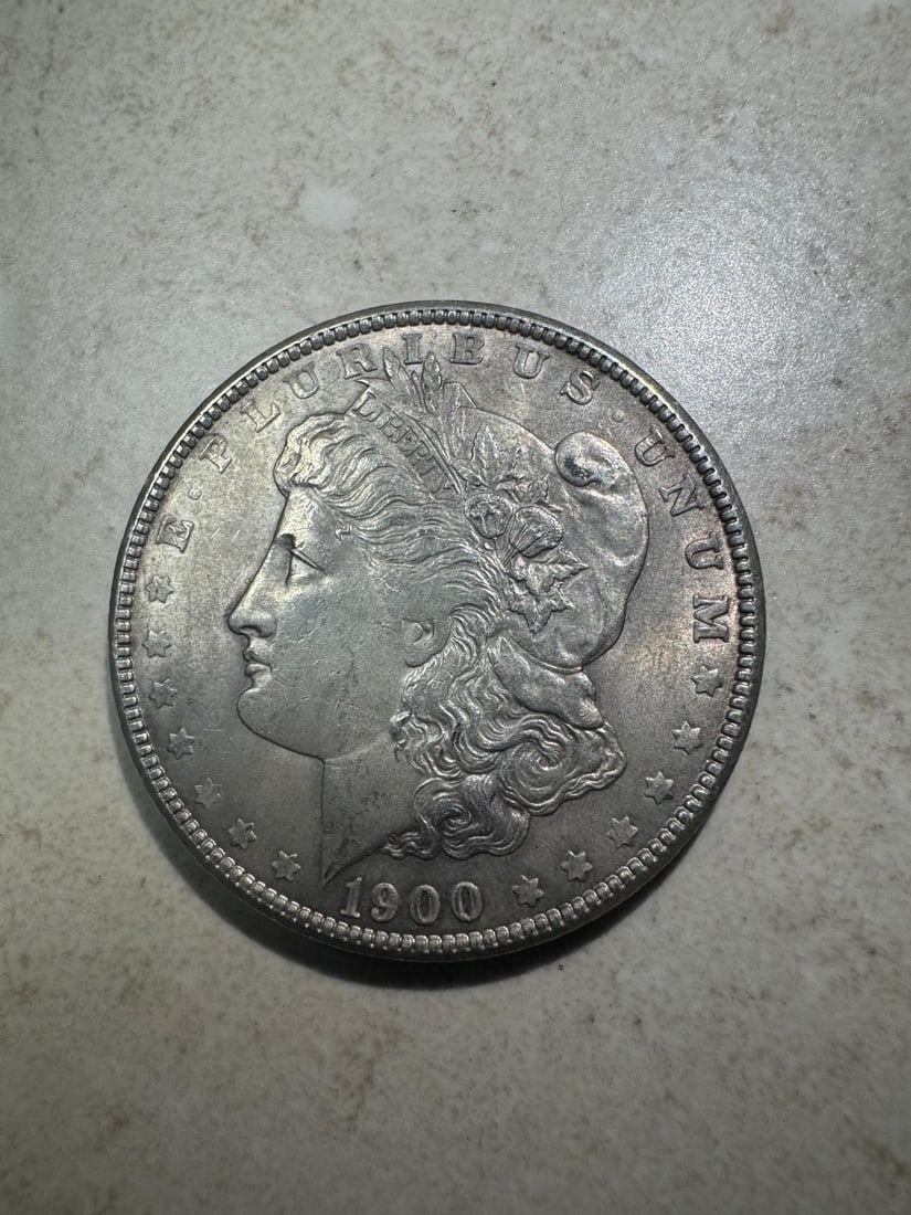 1900 Morgan Dollar About Uncirculated: The 1900 Morgan Dollar About Uncirculated (Non-Graded) is a lightly circulated coin with minimal wear and traces of original luster, offering strong eye appeal.