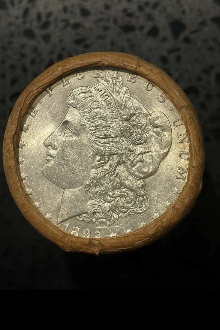 BU $10 Morgan Silver Dollar Roll 1892 & CC Ends: An original Brilliant Uncirculated (BU) sealed roll of Morgan Silver Dollars, featuring an 1892 coin on one end and a Carson City (CC) Mint coin on the opposite end. The roll remains sealed, with only