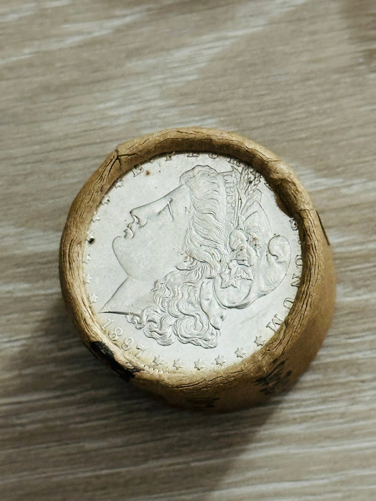 BU $10 Morgan Silver Dollar Roll 1897 & 1897 Ends: An original Brilliant Uncirculated (BU) sealed roll of Morgan Silver Dollars, featuring an 1897 coin on one end and an 1897 coin on the opposite end. The roll remains sealed, with only the front and b