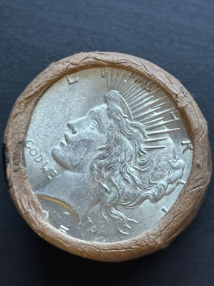 BU $10 Peace Silver Dollar Roll 1925 & 1923 Ends: An original Brilliant Uncirculated (BU) sealed roll containing 10 Peace Silver Dollars, featuring a 1925 coin on one end and a 1923 coin on the other. The roll remains sealed to ensure the interior co