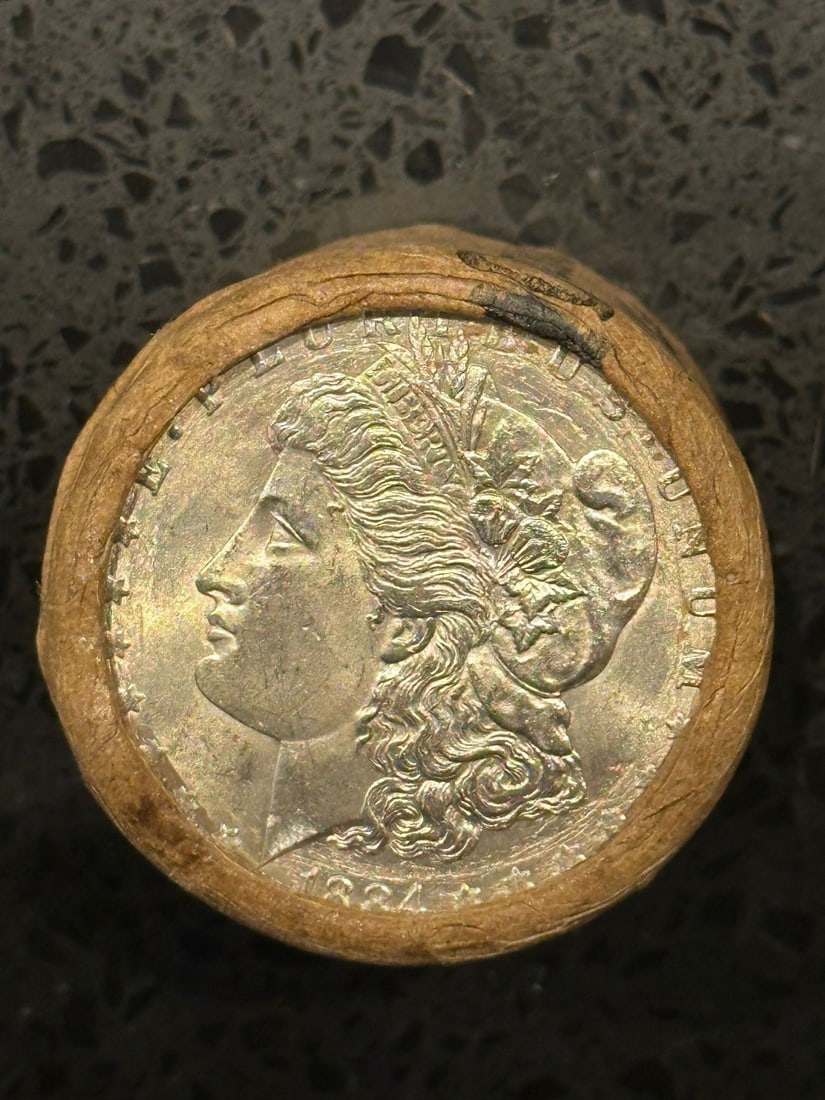 BU $10 Morgan Silver Dollar Roll 1884 & P Ends: An original Brilliant Uncirculated (BU) sealed roll of Morgan Silver Dollars, featuring an 1884 coin on one end and a Philadelphia (P) Mint coin on the opposite end. The roll remains sealed, with only