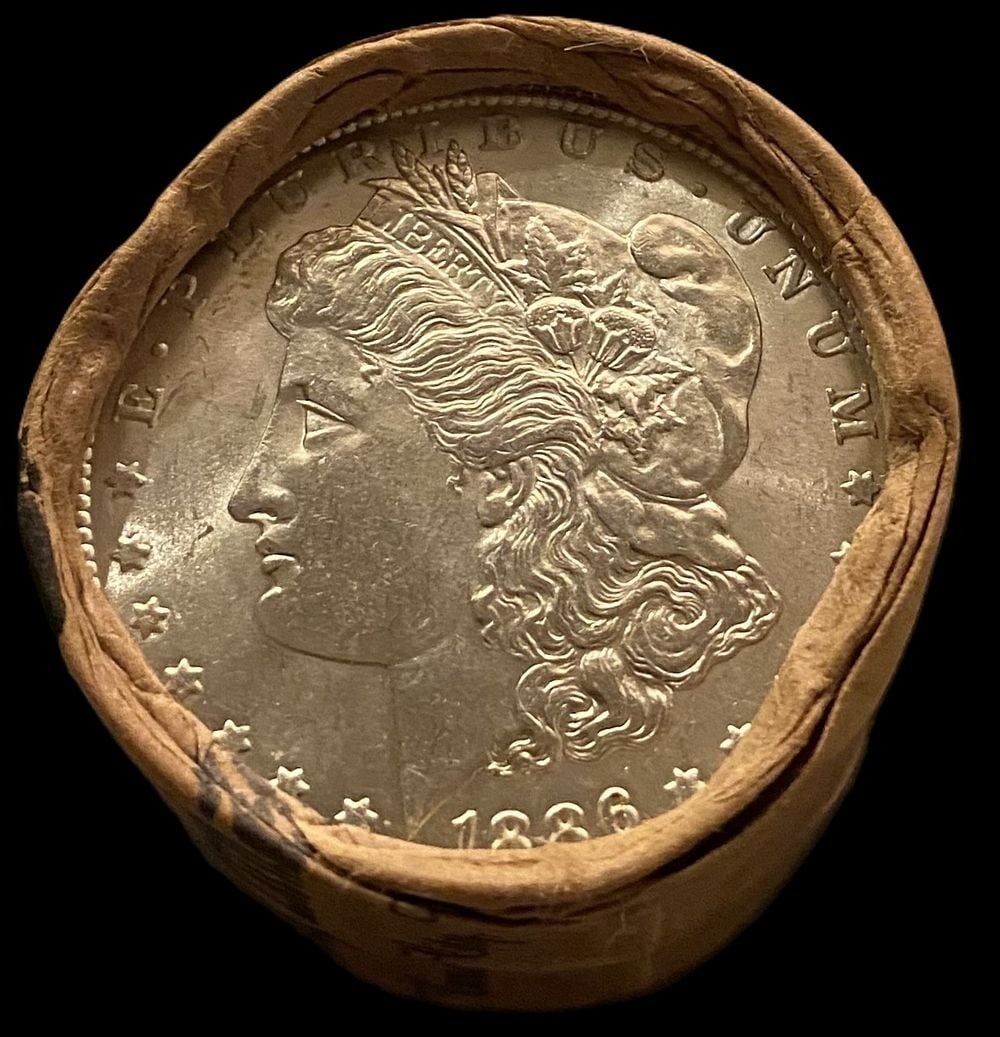BU $10 Morgan Silver Dollar Roll 1886 & 1897 Ends: An original Brilliant Uncirculated (BU) sealed roll of Morgan Silver Dollars, featuring an 1886 coin on one end and an 1897 coin on the opposite end. The roll remains sealed, with only the front and b