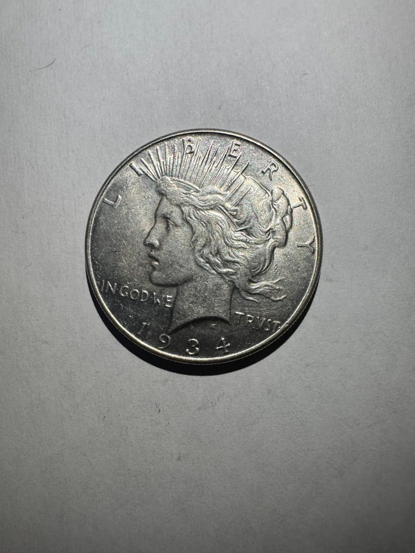 1934- Peace Dollar BU: The 1934 Peace Dollar is a better-date issue with strong collector demand. In Brilliant Uncirculated (BU) condition, it displays sharp strike and full mint luster. Composed of 90% silver, it contains 