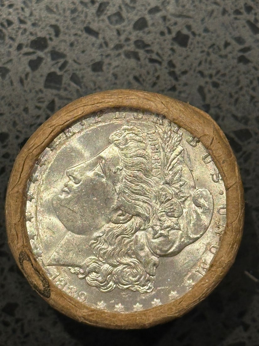 BU $10 Morgan Silver Dollar Roll 1889 & CC Ends: An original Brilliant Uncirculated (BU) sealed roll of Morgan Silver Dollars, featuring an 1889 coin on one end and a Carson City (CC) Mint coin on the opposite end. The roll remains sealed, with only