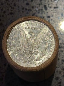BU $10 Morgan Silver Dollar Roll S & CC Ends: An original Brilliant Uncirculated (BU) sealed roll of Morgan Silver Dollars, featuring a San Francisco (S) Mint coin on one end and a Carson City (CC) Mint coin on the opposite end. The roll remains 