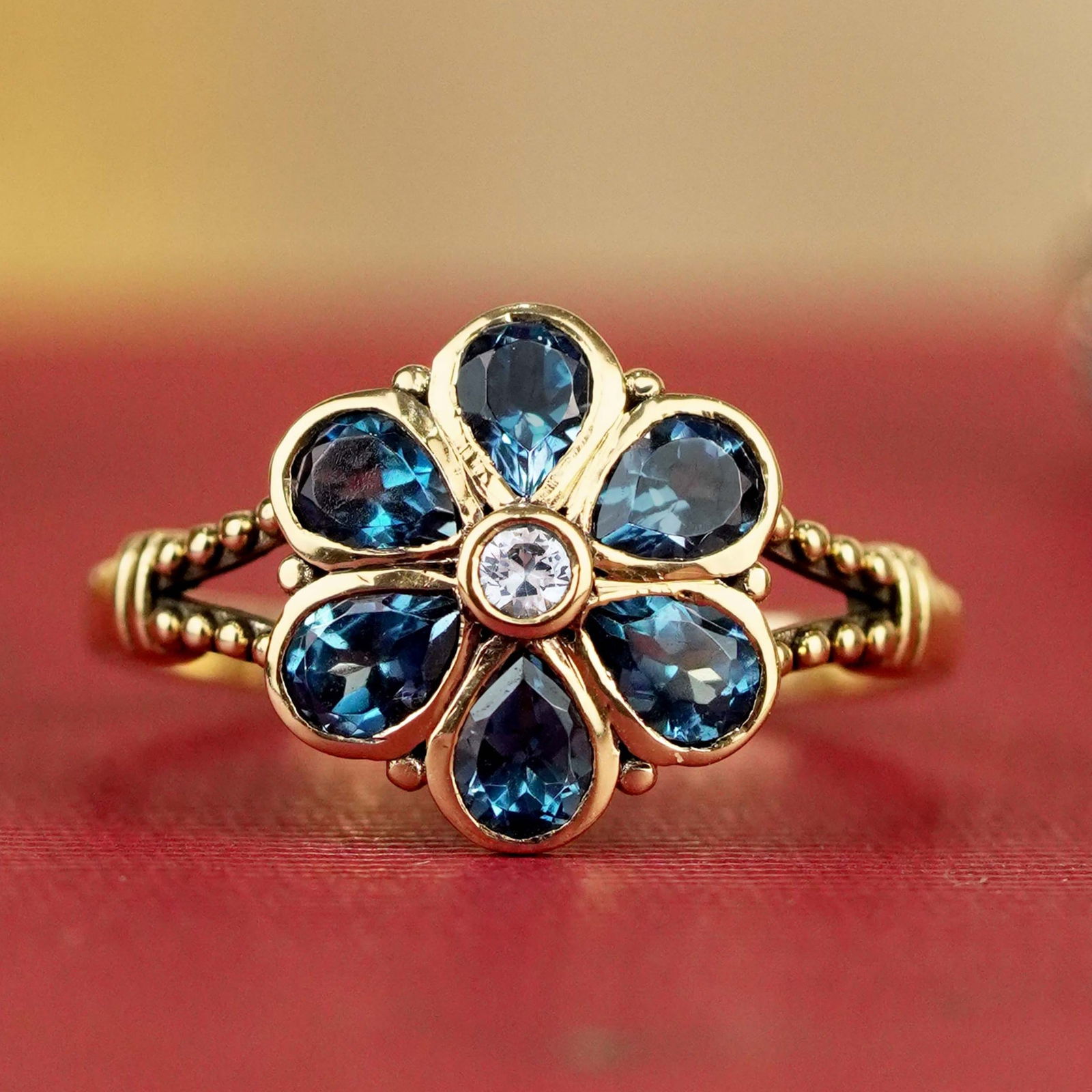 9K Yellow Gold Natural White Sapphire and London Blue Topaz Vintage Style Floral Ring: CHARACTERISTICSOrigin: ThailandMetal: Solid 9K Yellow GoldRing Size: US 7Total Gemstones Weight: 1.55 carat. (approx.)Total Gram Weight: 2.11 g. (approx.)*Pictures have been enlarged to show details*P