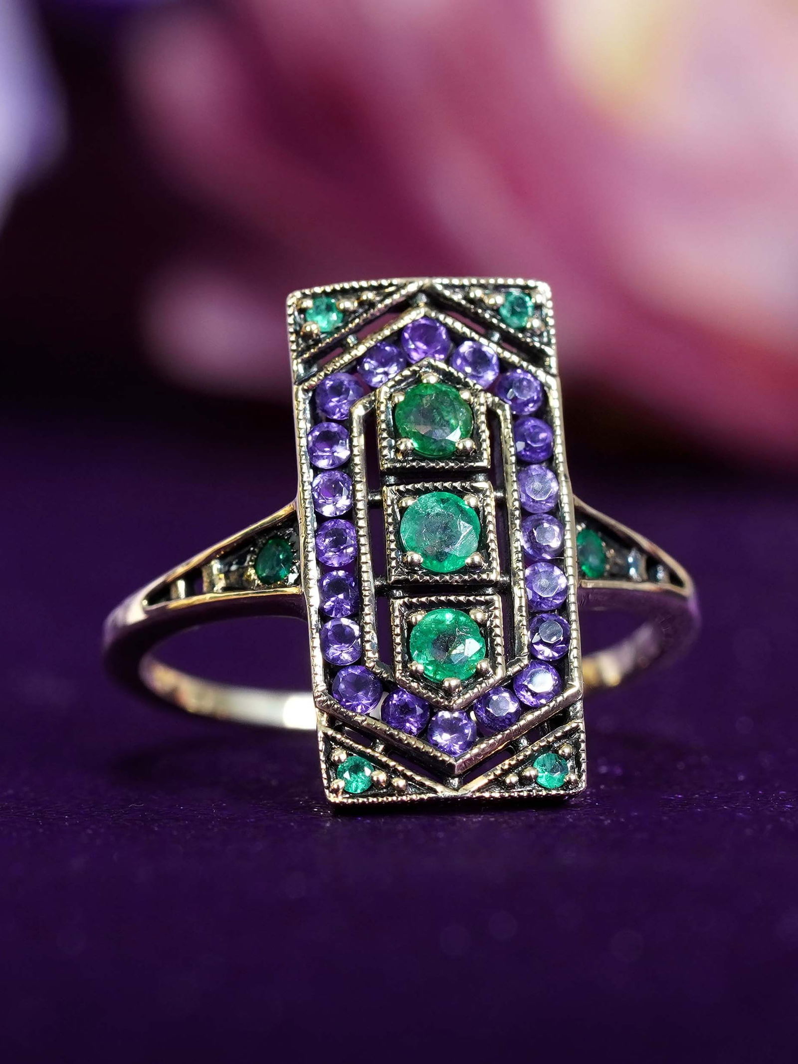 9K Yellow Gold Emerald and Amethyst Art Deco Style Ring: Ring InformationStyle: Art-decoMetal: 9K Yellow GoldTotal weight: 2.21 g. (approx. total weight)Size: US7Center Gemstones Type: EmeraldShape: RoundSize: 2.5 mm.Number: 3Weight: 0.25 Ca